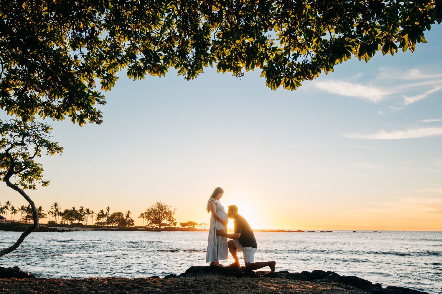 Romantic beach photoshoot at sunset with silhouetted trees and ocean backdrop at Kukio Beach, Kona, Big Island Hawaii.