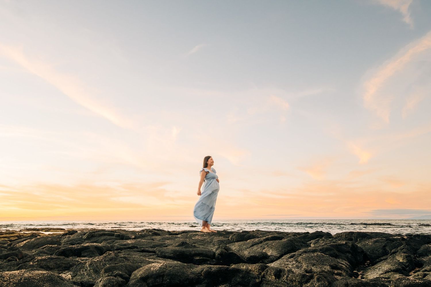 Dreamy beach photography session with dramatic sunset sky and rocky shoreline at Kukio Beach, Kona, Big Island Hawaii.