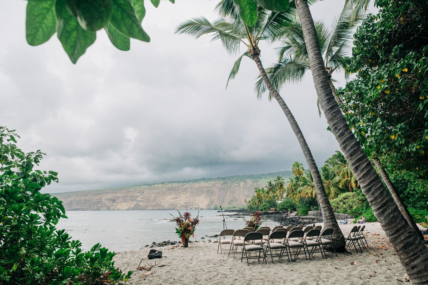 Tropical beach wedding setup with chairs and palm trees along the shore in Kona, Big Island of Hawaii.