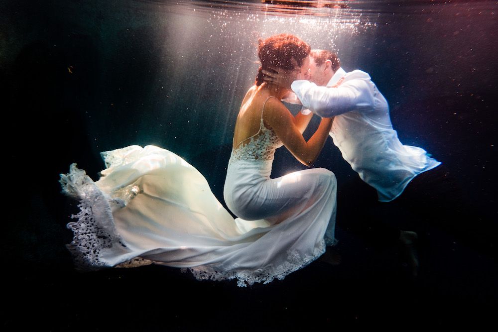 Underwater wedding photography series showing flowing white dress in deep blue water in Kona, Big Island of Hawaii.