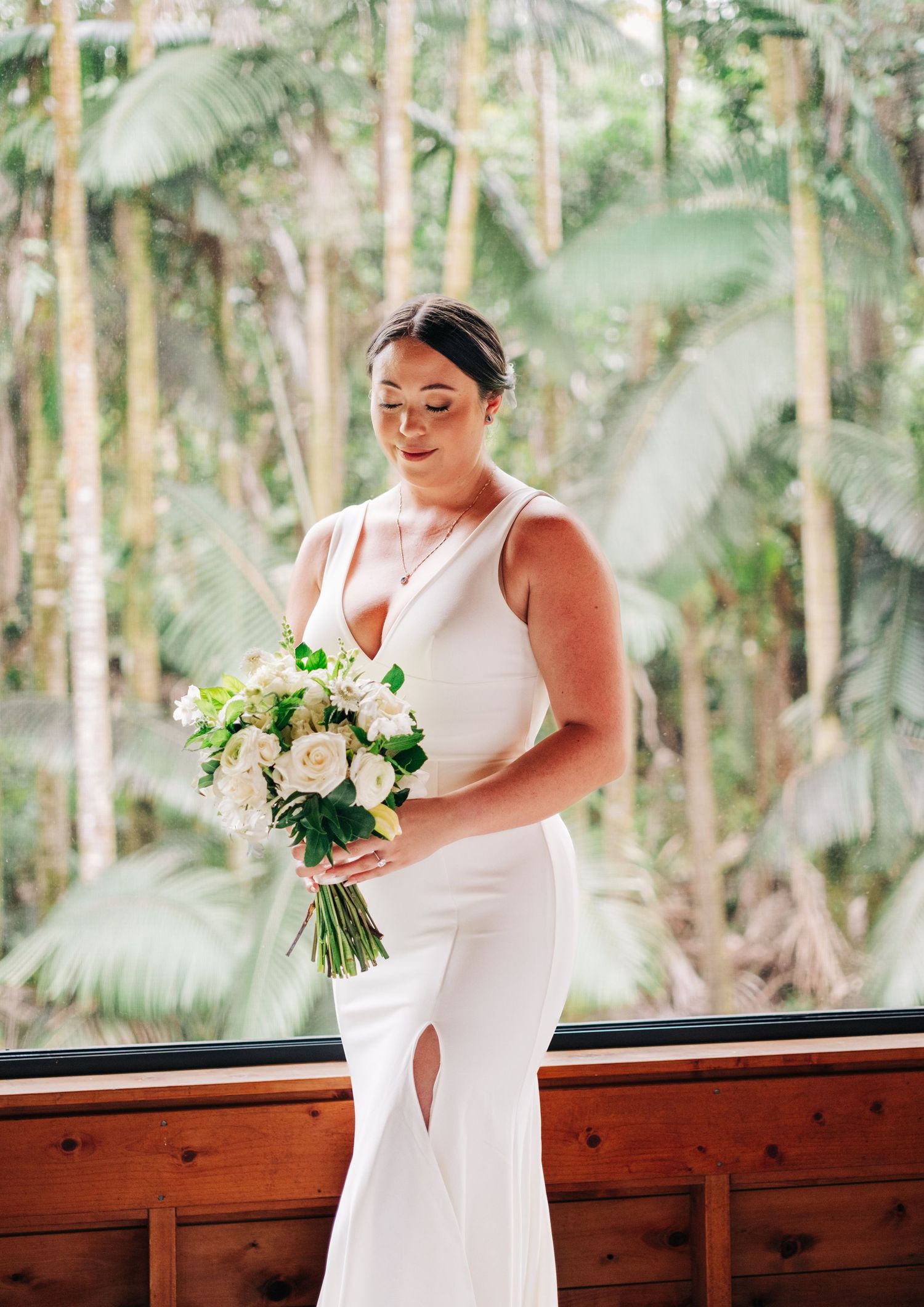 Elegant white bouquets sit ready on wooden railing with tropical foliage backdrop at the Falls at Reeds Island, Hilo, Big Island of Hawaii.