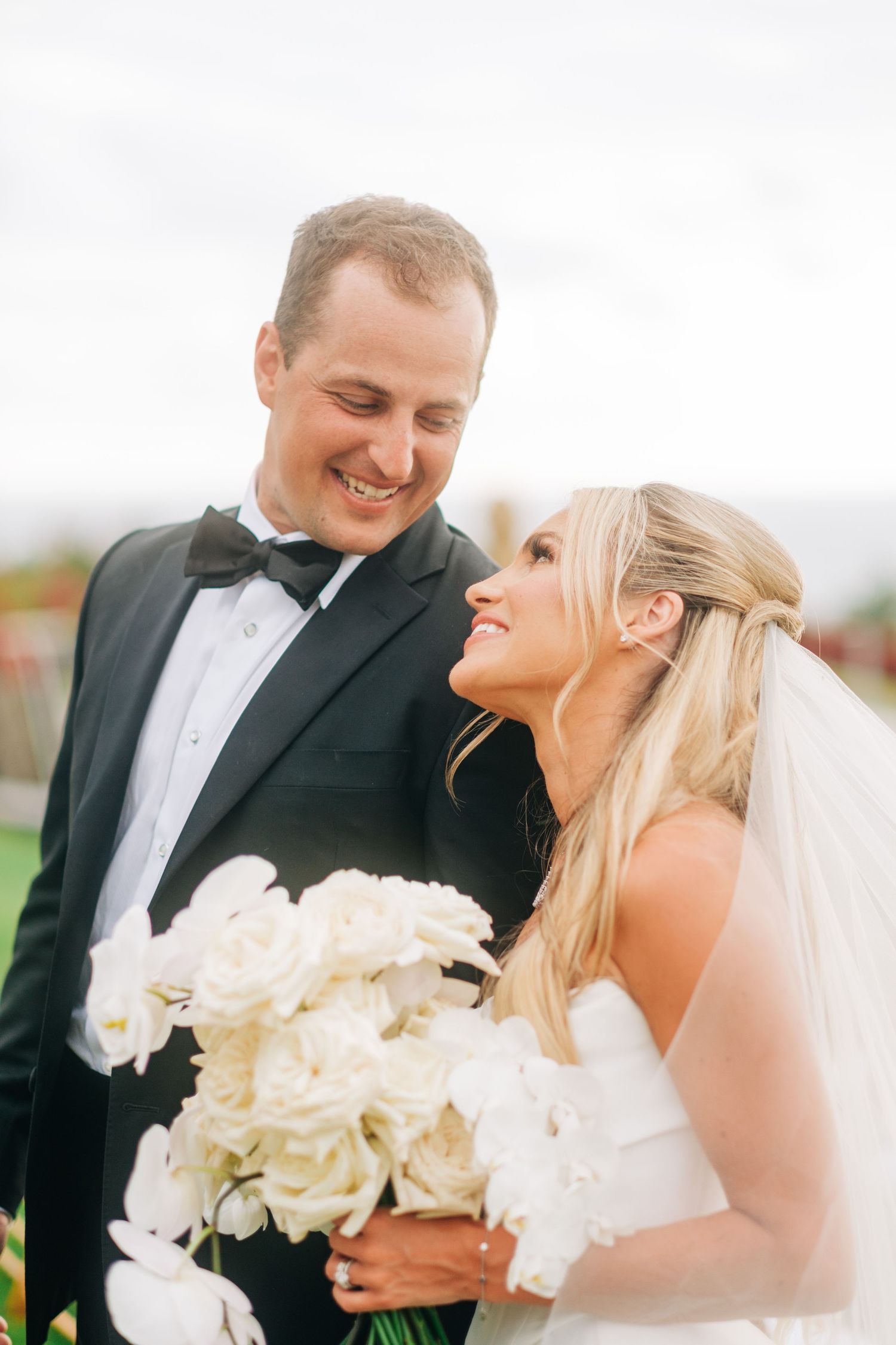 Joyful wedding couple shares intimate moments while holding white floral bouquet at Kohanaiki, Kona, Big Island of Hawaii.