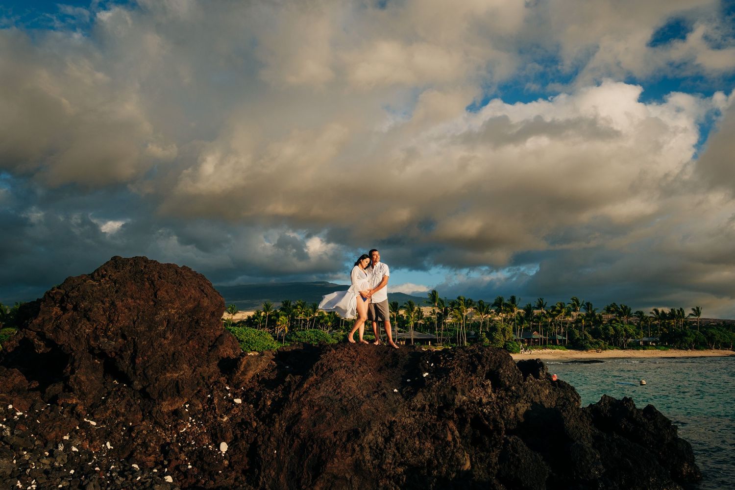 Panoramic oceanfront wedding photography session against dramatic cloudy skies and volcanic rocks at Kukio Beach, Big Island of Hawaii.