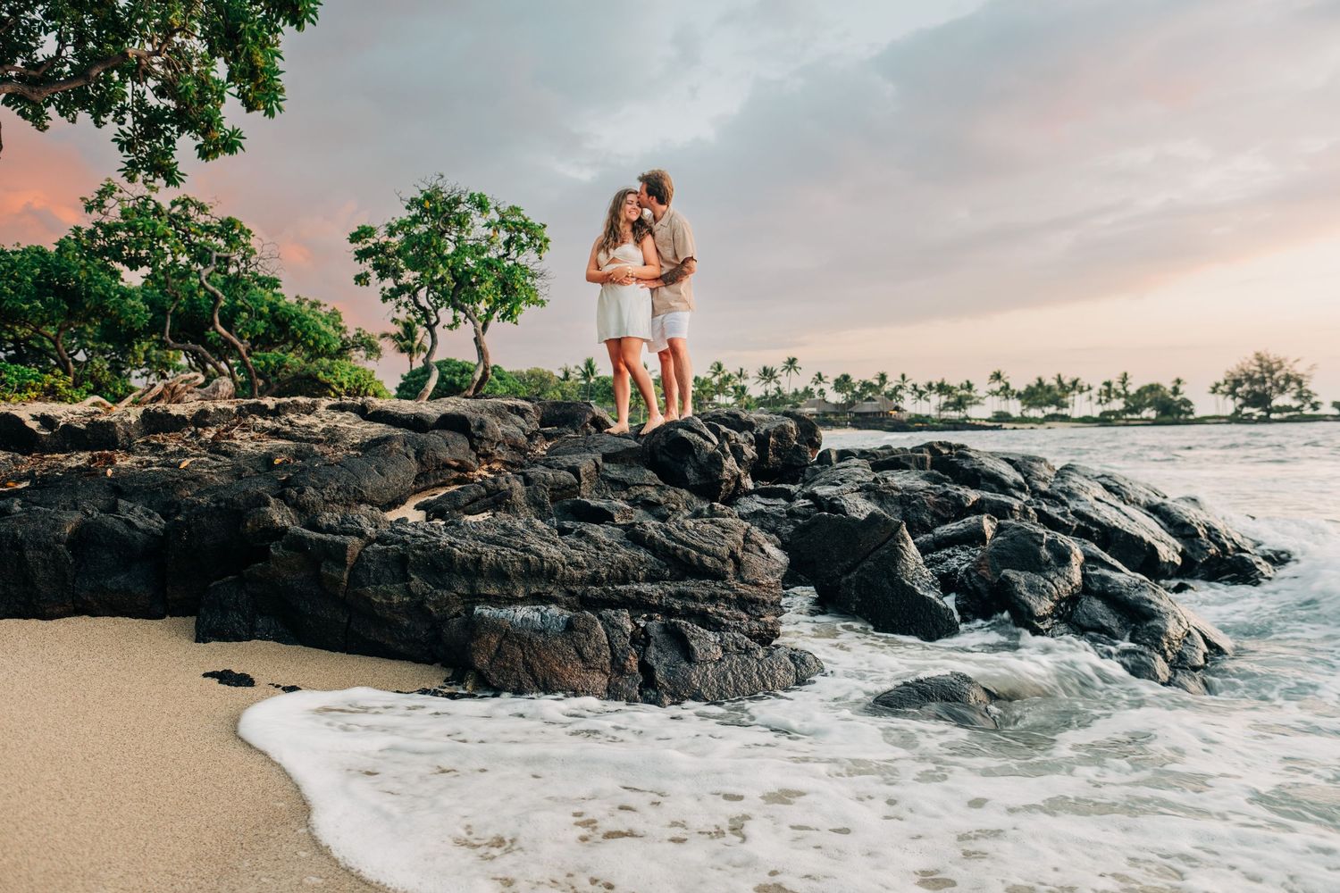 Rocky beach landscape with waves crashing against black volcanic rocks during sunset at Kukio Beach, Kona, Big Island of Hawaii.