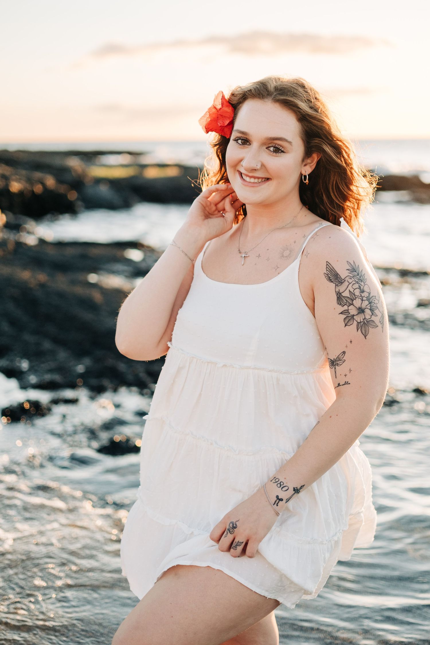 Woman in white dress poses on rocky beach at sunset at Mauna Lani, Big Island of Hawaii.