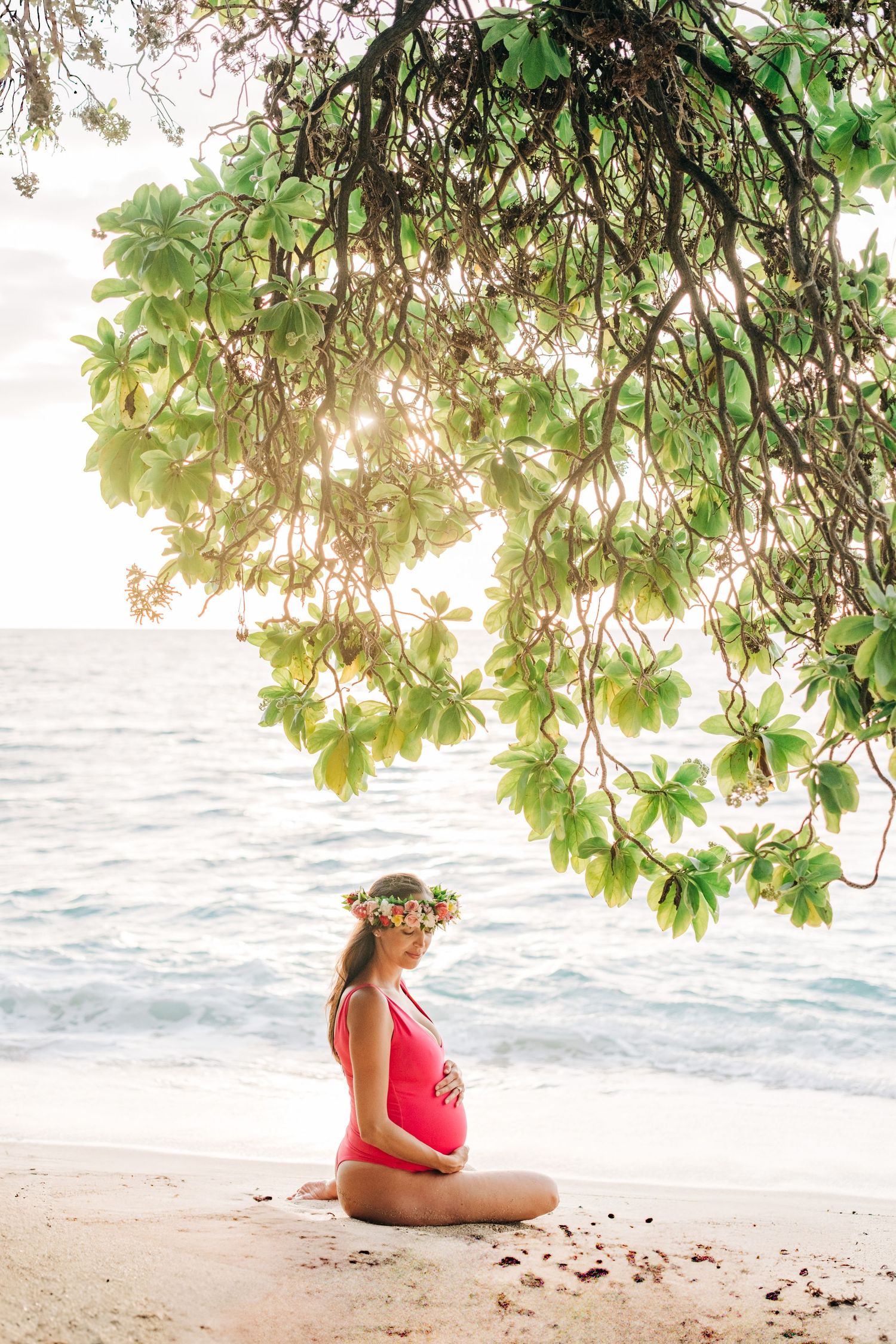 Peaceful beach maternity session under tropical foliage at sunset at Kukio Beach, Kona, Big Island Hawaii.
