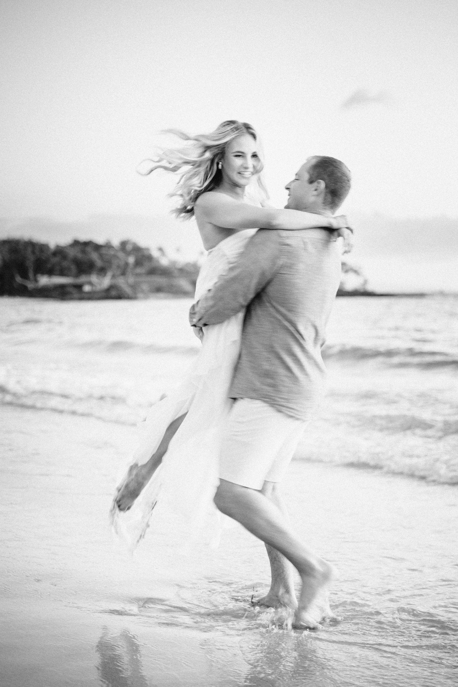Black and white photos of a couple playing and embracing in the ocean waves at Mauna Kea Beach Resort, Big Island Hawaii.