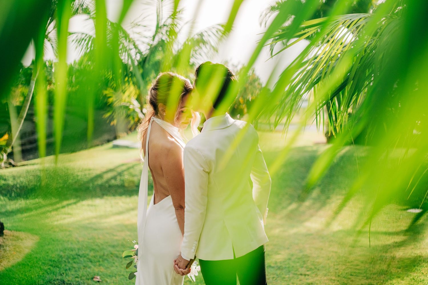 Ethereal wedding photos through palm fronds creating a dreamy green filtered effect at Holualoa Inn, Kona, Big Island Hawaii.
