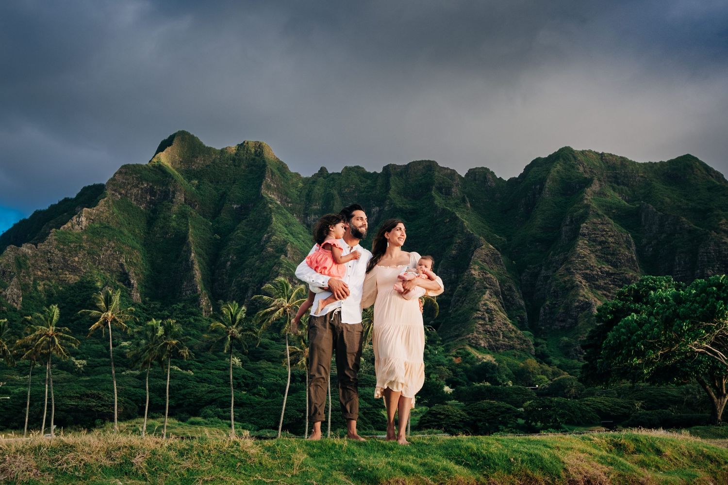 Scenic Kualoa mountain landscape with palm trees and dramatic clouds in Hawaii.
