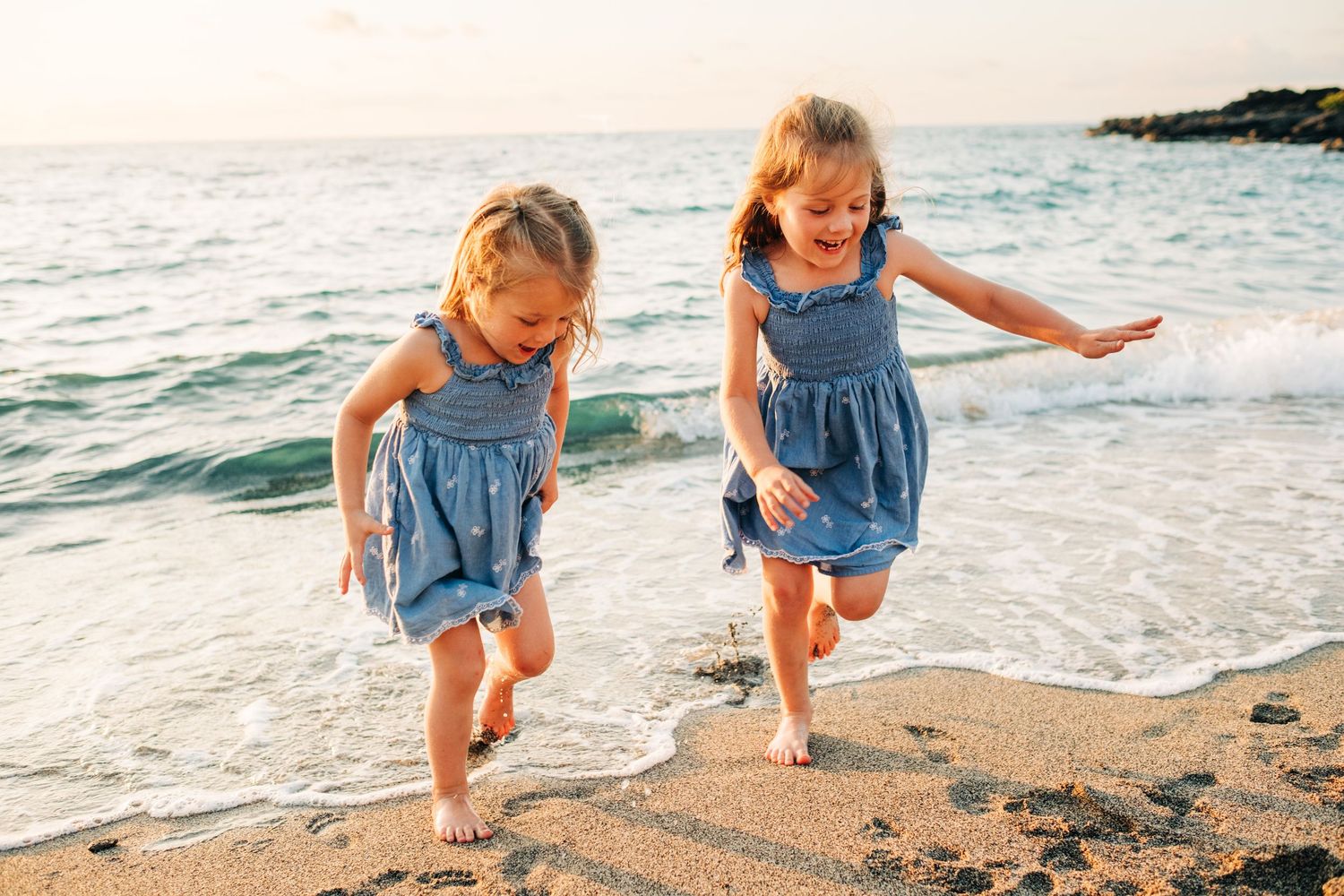 Children playing and exploring along sandy beach at sunset at Kukio Beach, Big Island Hawaii.