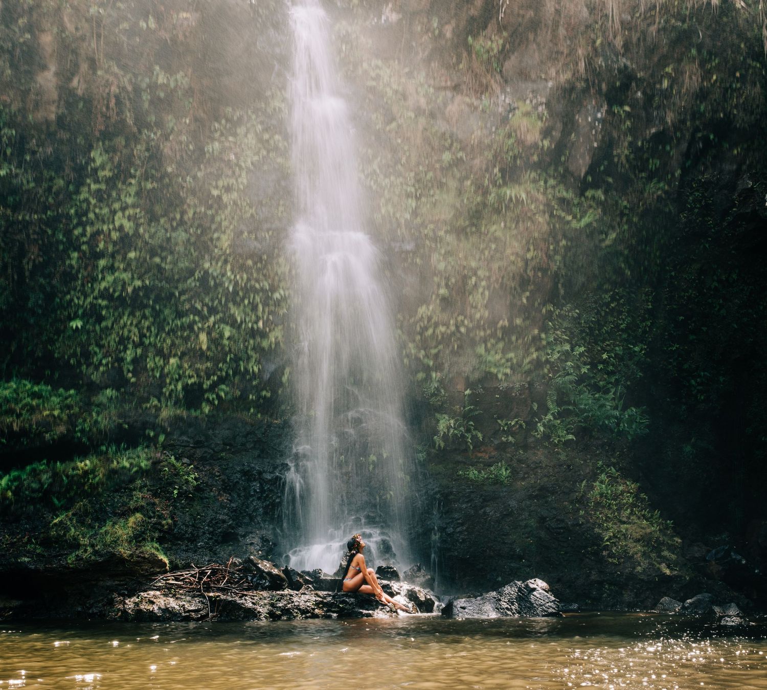 Majestic waterfall cascades through lush Hawaiian rainforest creating a misty atmosphere in Hilo, Big Island of Hawaii.