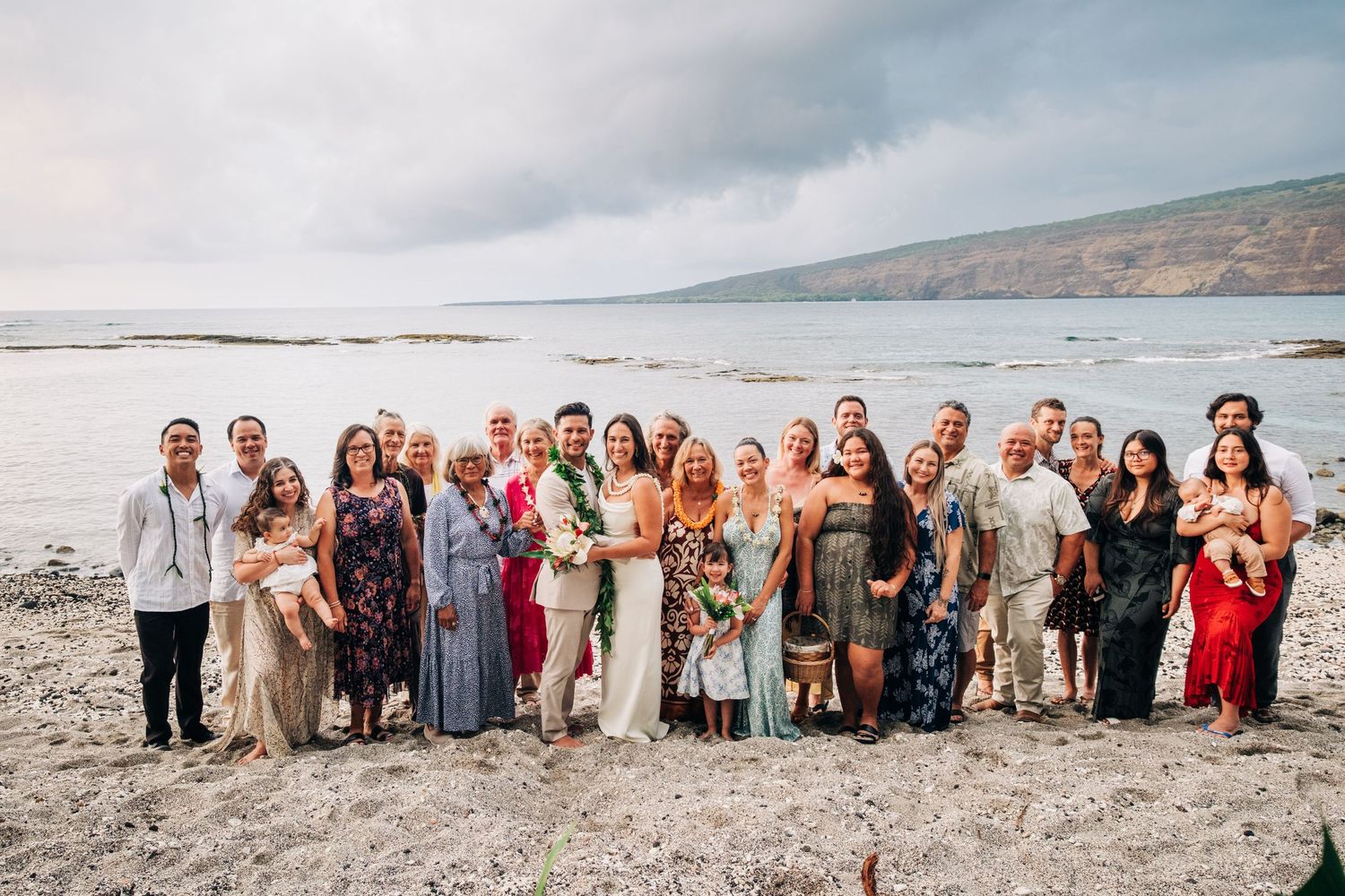 Large wedding party group photo on Hawaiian beach with ocean backdrop in Kona, Big Island of Hawaii.