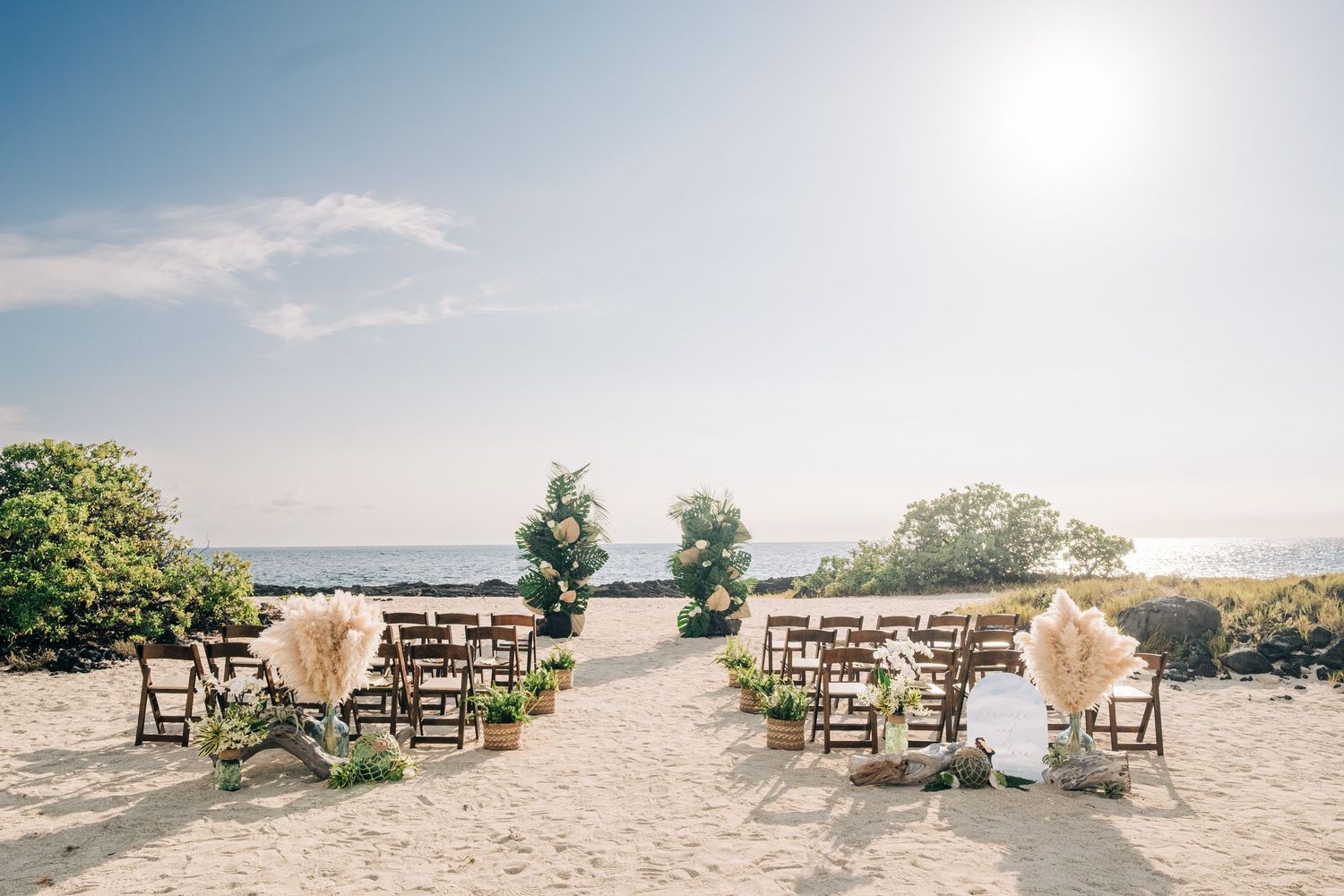 Beach wedding ceremony setup with wooden chairs and ocean view at Kona Salt Farm, Big Island of Hawaii.