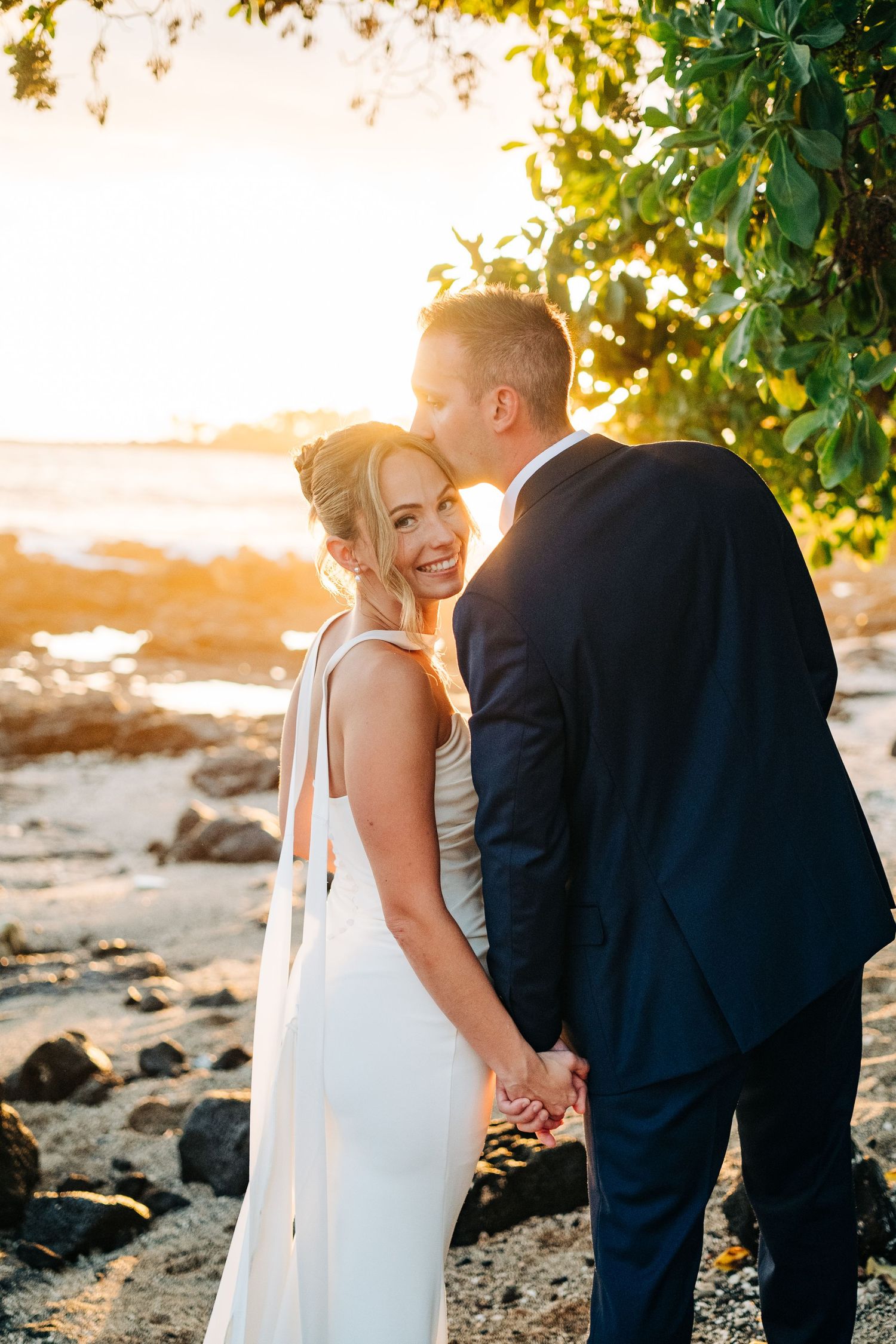 Golden hour wedding photos on rocky Hawaiian beach with lush foliage near Papa Kona, Big Island Hawaii.