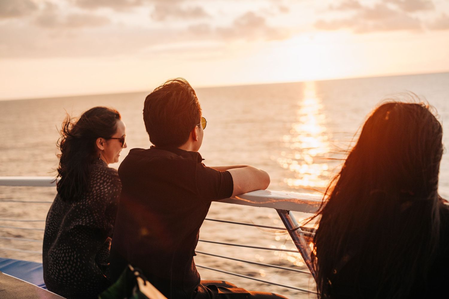 Silhouettes of people enjoying a golden sunset over the ocean in Kona, Big Island of Hawaii.