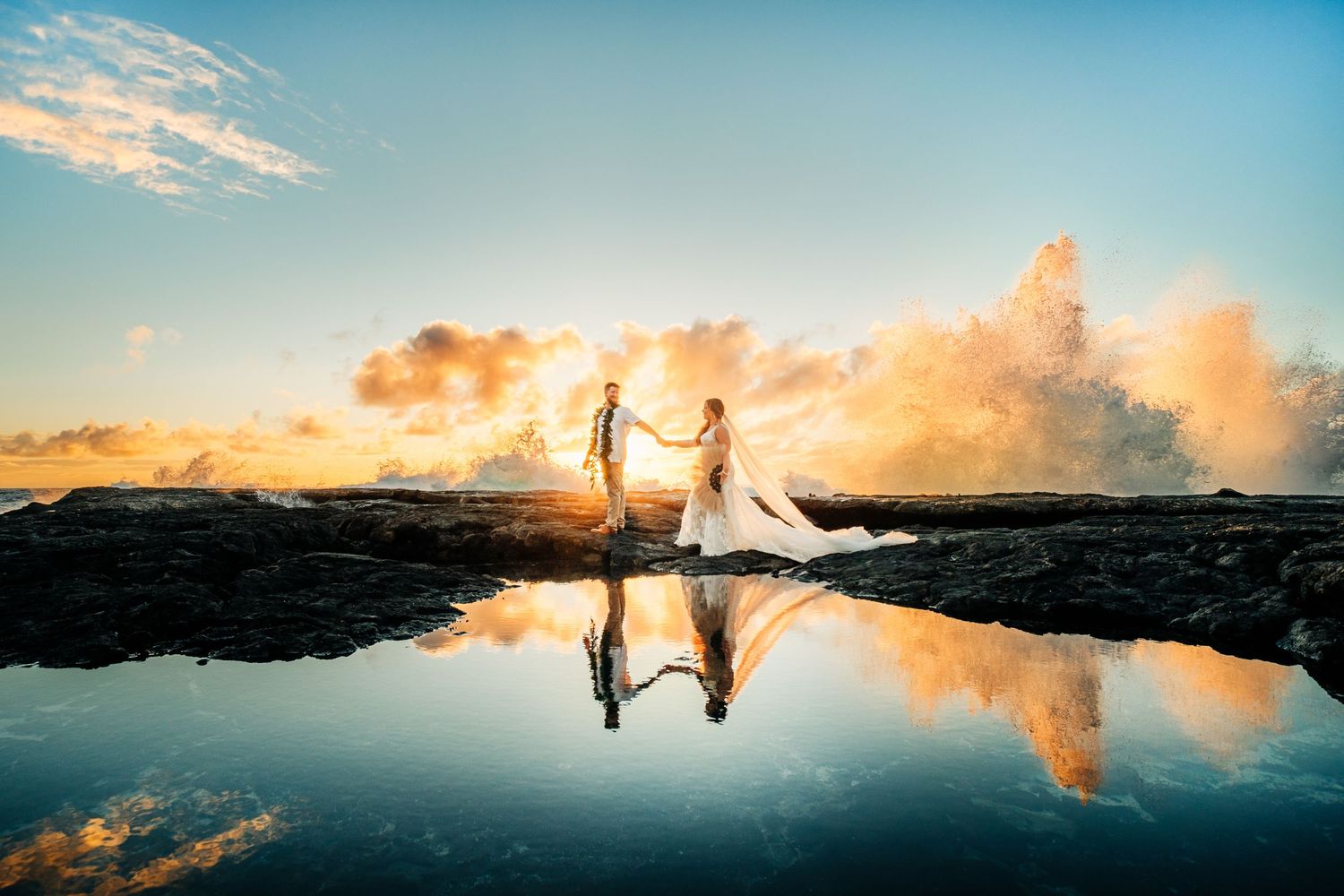 Silhouettes reflected in still water against a dramatic sunset sky on rocky coastline at Kona Salt Farm, Big Island Hawaii.