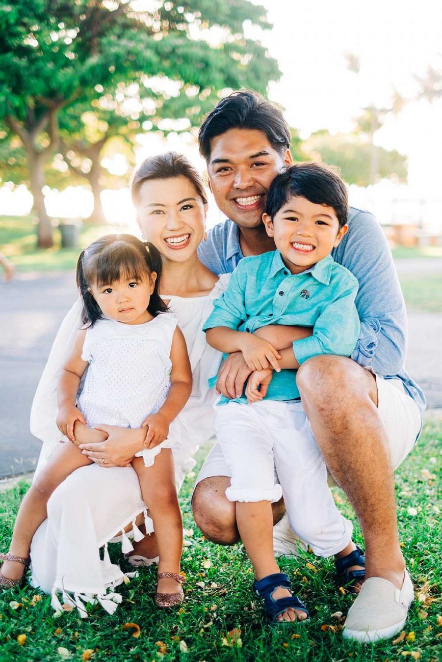 Family sitting together outdoors on grass during golden hour sunset in Waikiki, Oahu.