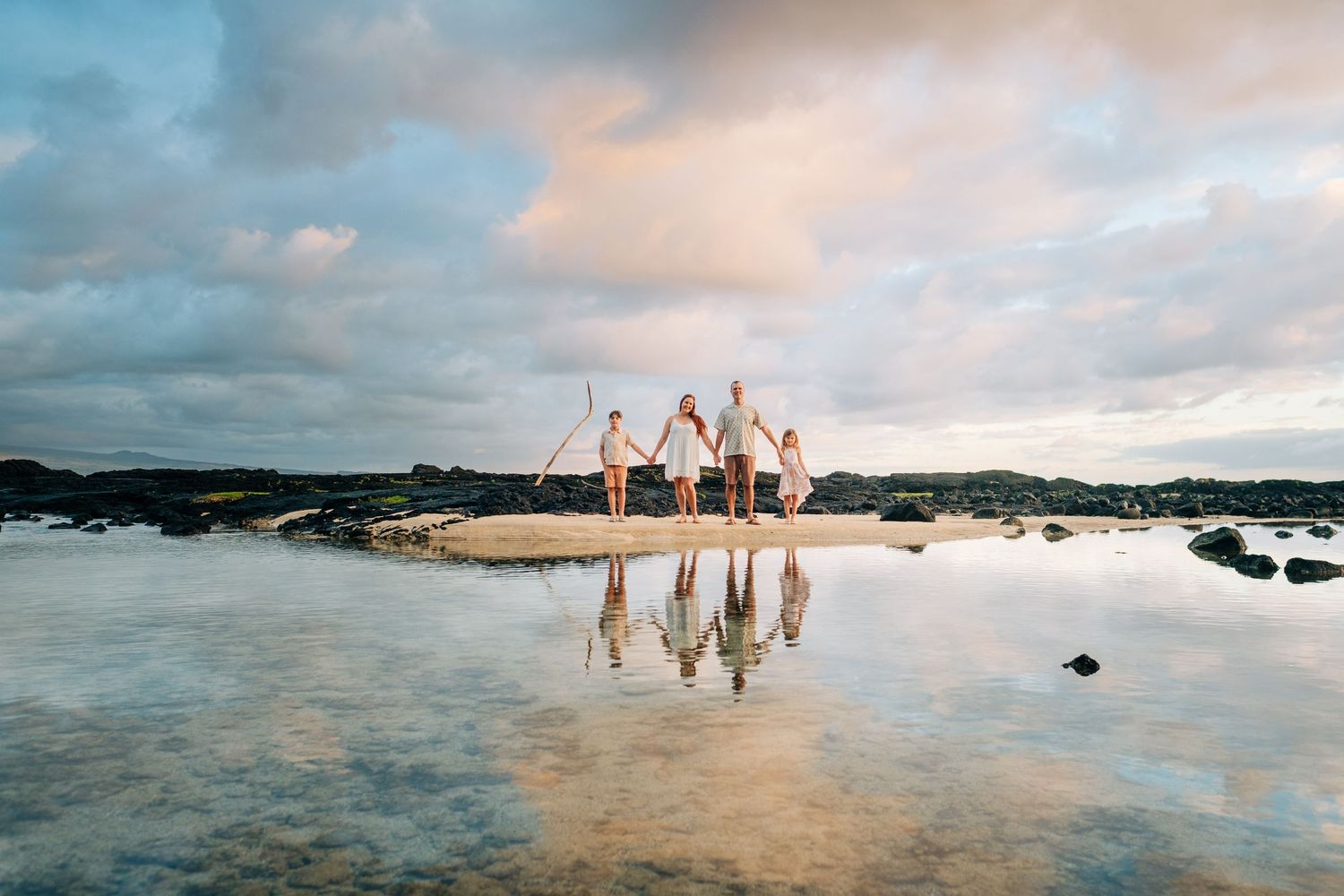 Reflective water creates mirror images of people walking on a beach at sunset at Hilo, Big Island of Hawaii.