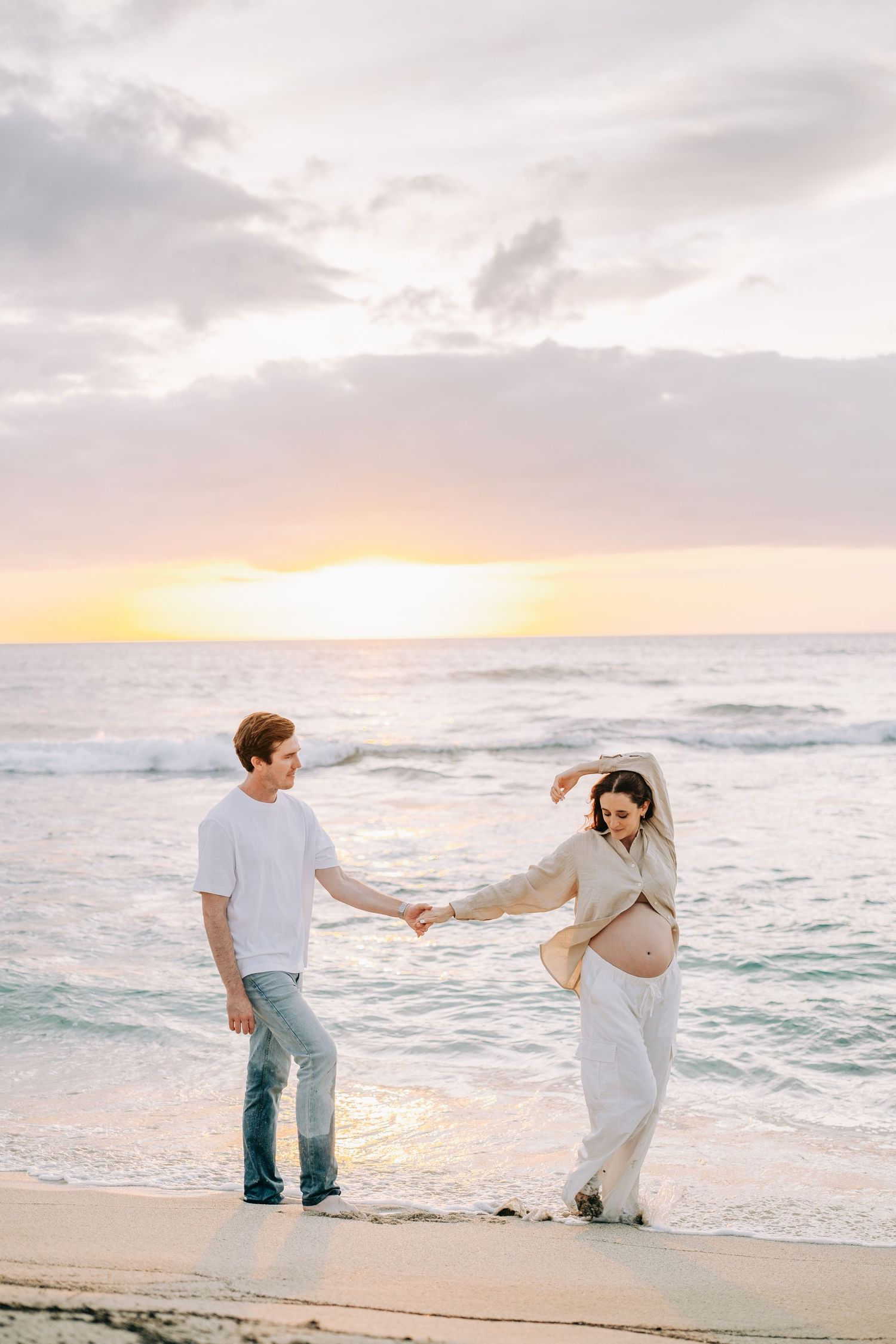 Couple shares romantic moment on sandy beach during golden hour at Mauna Kea Beach, Big Island Hawaii.