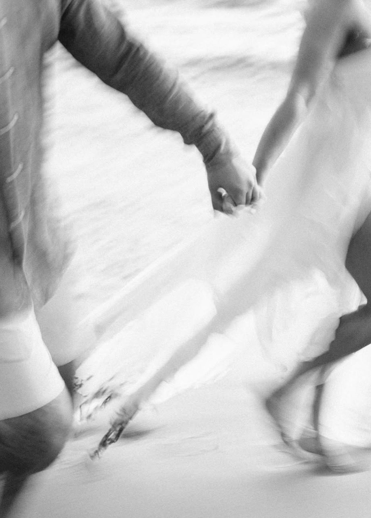 Abstract black and white motion blur of dancers moving across a white background at Mauna Kea Beach, Big Island Hawaii.