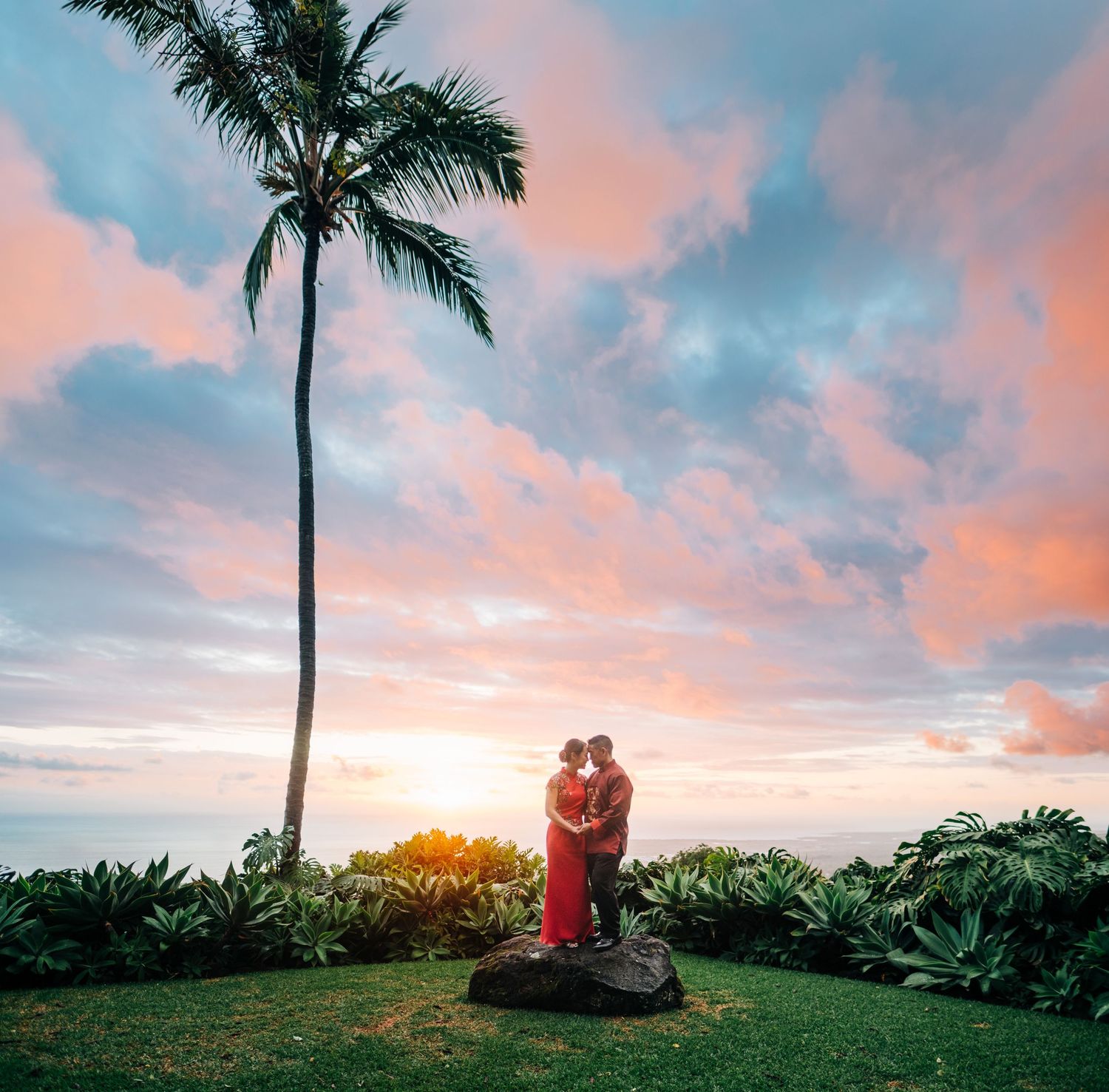 Tropical sunset wedding ceremony with palm trees and pink-orange sky at Holualoa Inn, Kona, Big Island Hawaii.