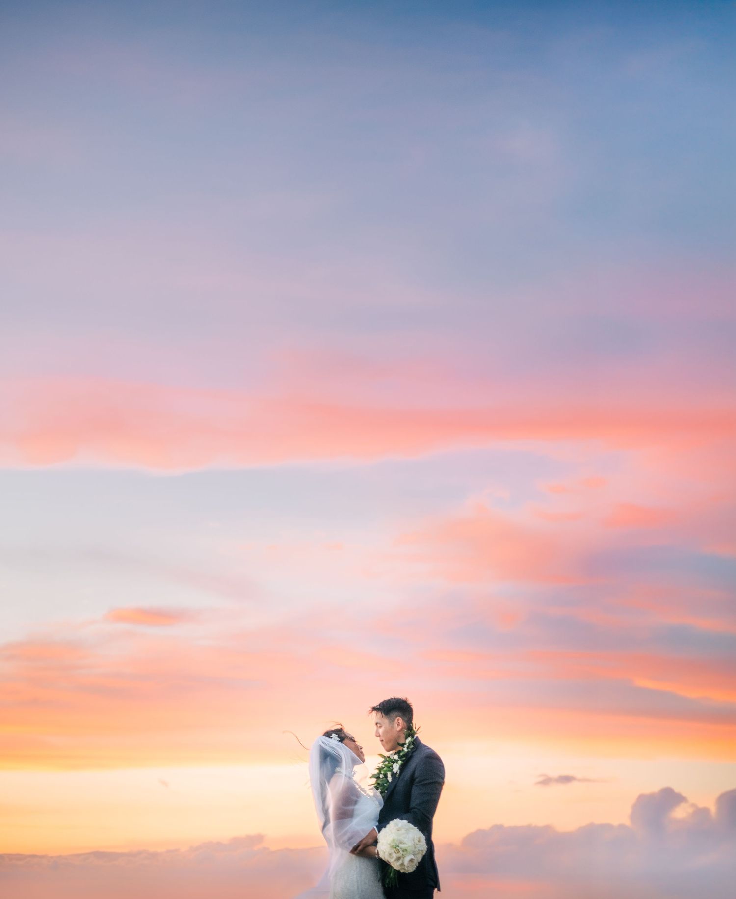 Wedding couple silhouetted against a vibrant orange and pink sunset sky in Waikoloa, Big Island of Hawaii.