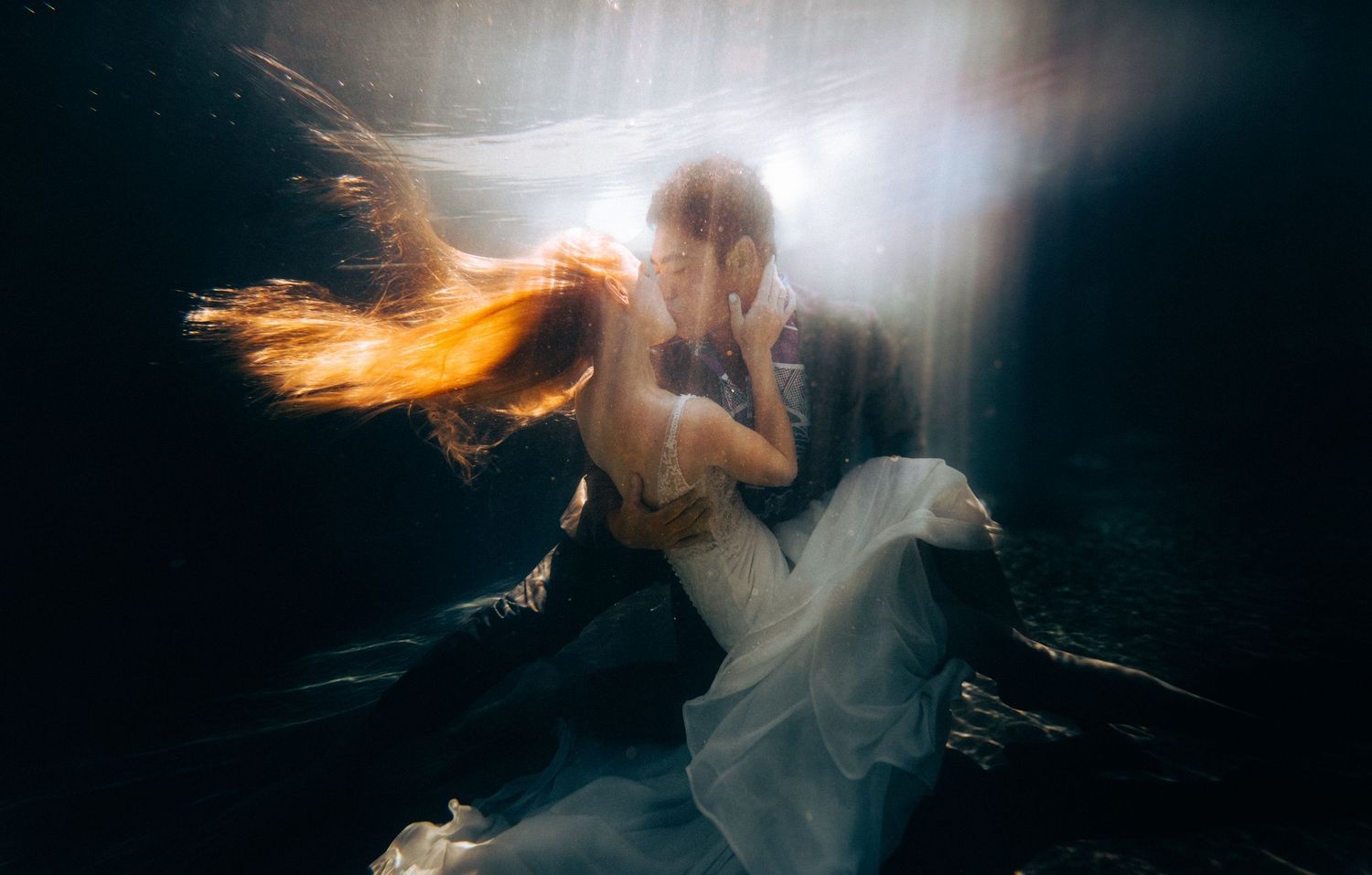 Artistic underwater portrait with flowing fabric and ethereal light beams. Big Island of Hawaii.