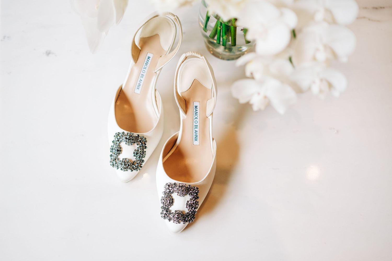 Elegant crystal-embellished bridal shoes arranged on white background. Kohanaiki wedding in Kona, Big Island.