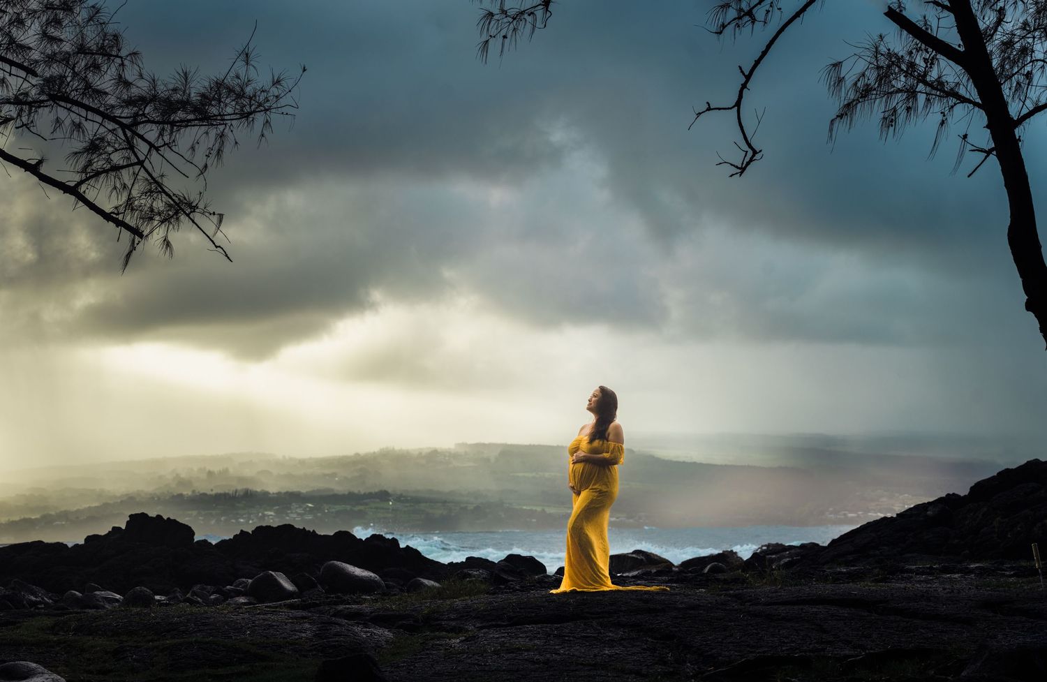 Silhouetted figure in yellow dress stands on rocky volcanic landscape at sunset in Hilo, Big Island of Hawaii.