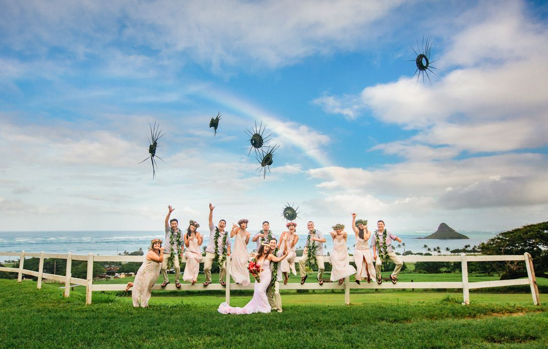 Wedding party celebration on a scenic coastal hilltop with blue skies at Kualoa Ranch, Oahu, Hawaii.