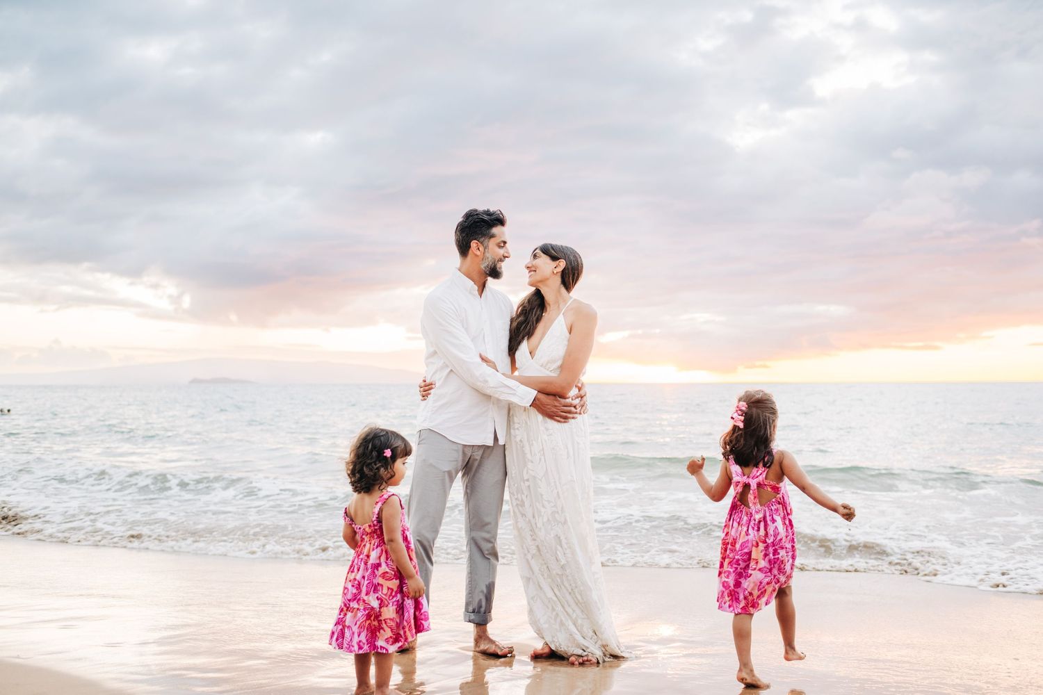 Family enjoying a stroll along a white sandy beach during golden hour on Wailea Beach in Maui.
