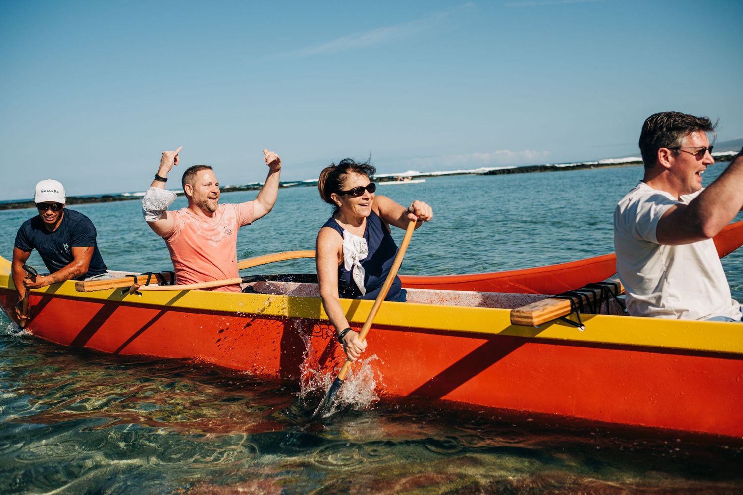Group enjoying a kayak adventure in bright orange boats on calm ocean waters at Mauna Lani Beach Resort.
