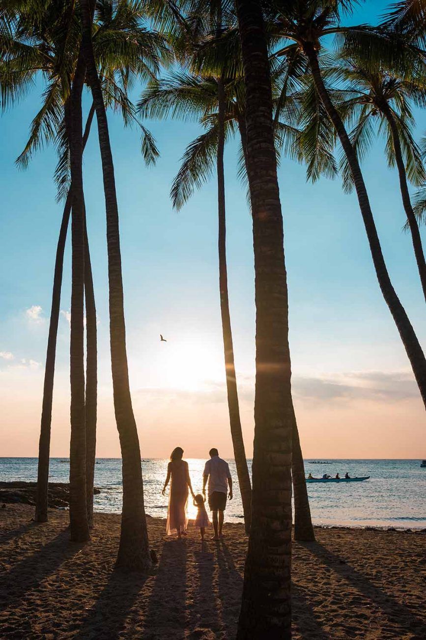 Silhouettes of palm trees frame a beach sunset with ocean view in Waikoloa, Big Island of Hawaii.
