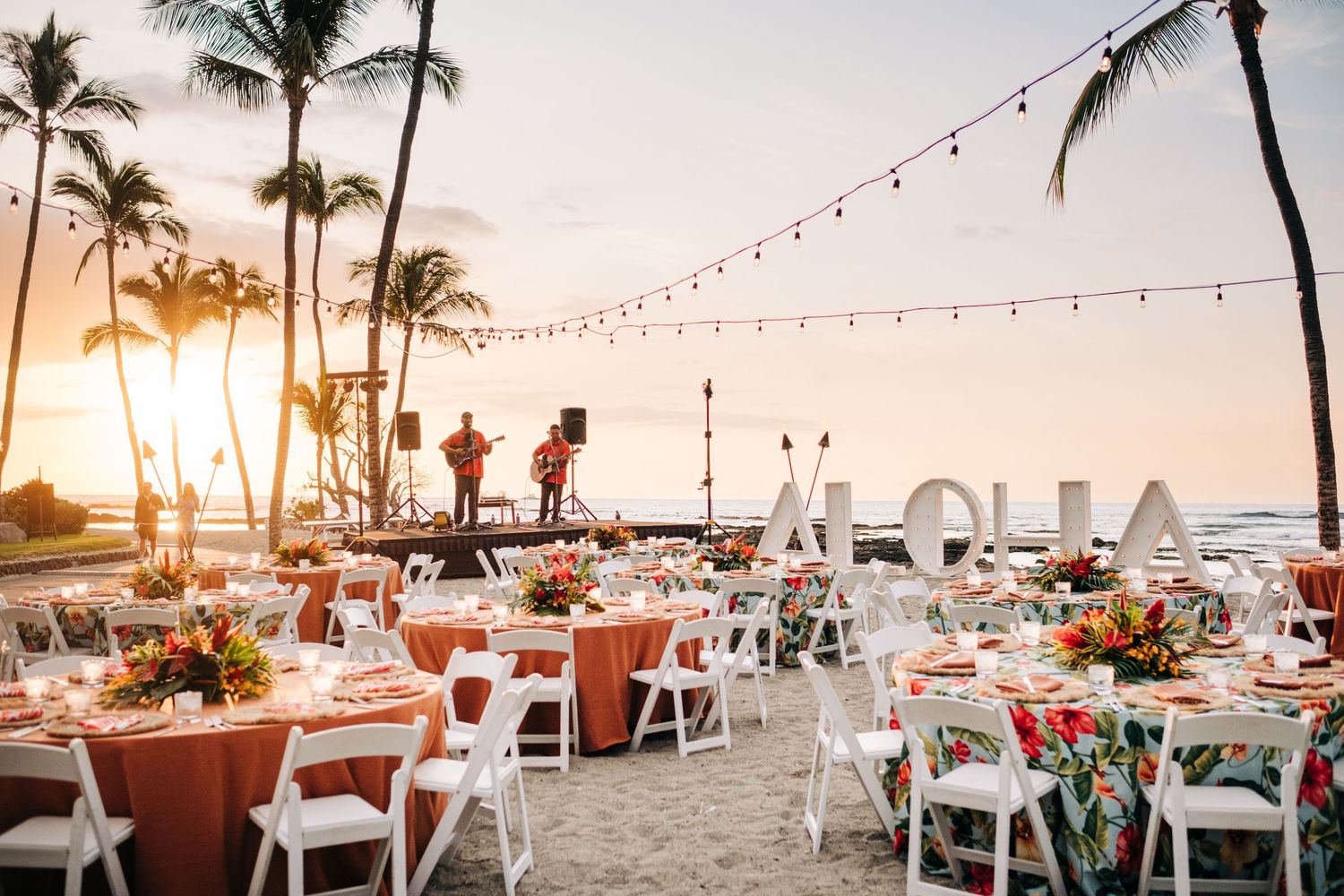 Event setup with string lights and palm trees at sunset at Mauna Lani Beach Resort.