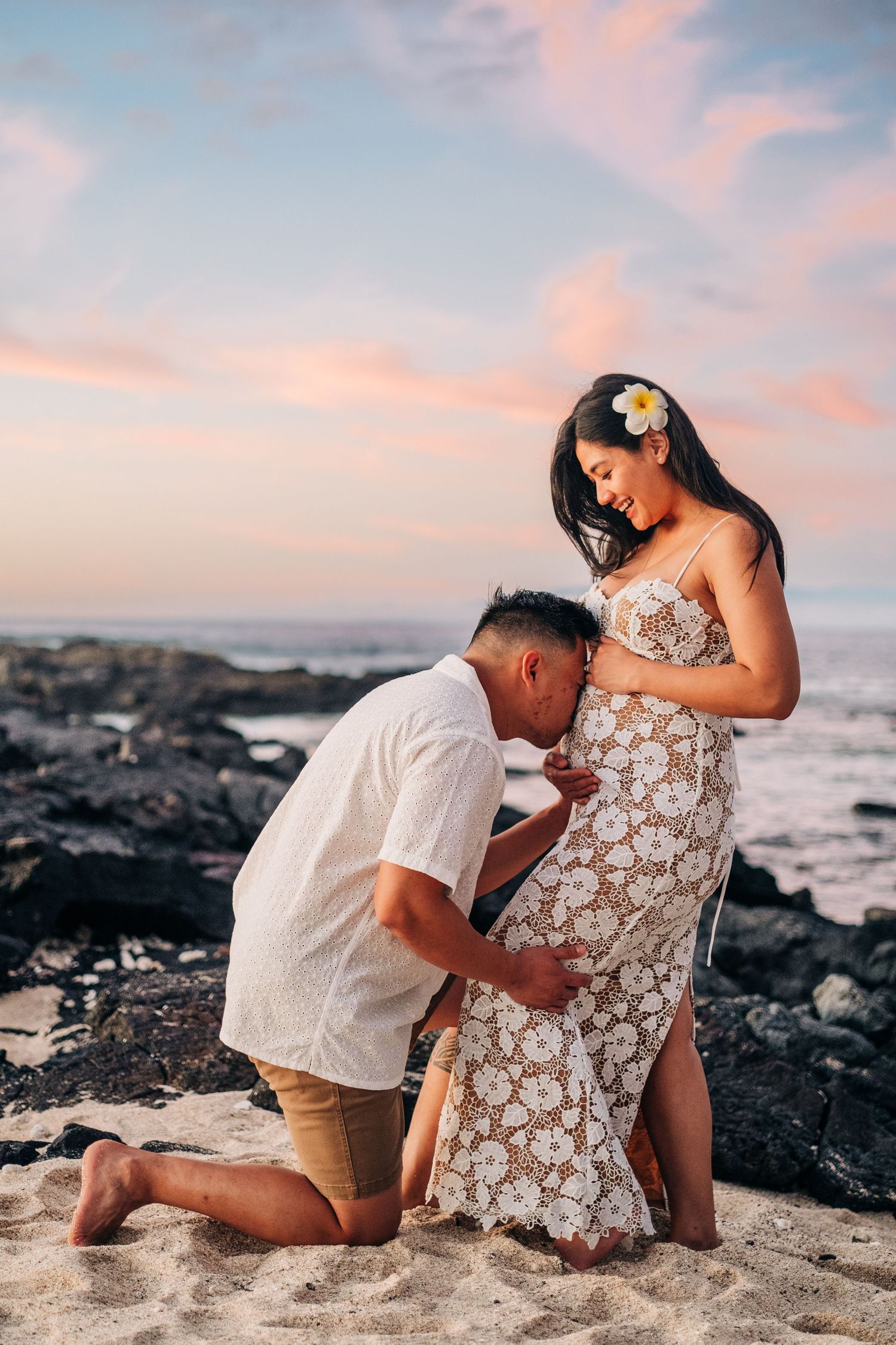 Intimate beach maternity photography session on black lava rocks at sunset at Kikaua Point Beach, Big Island of Hawaii.