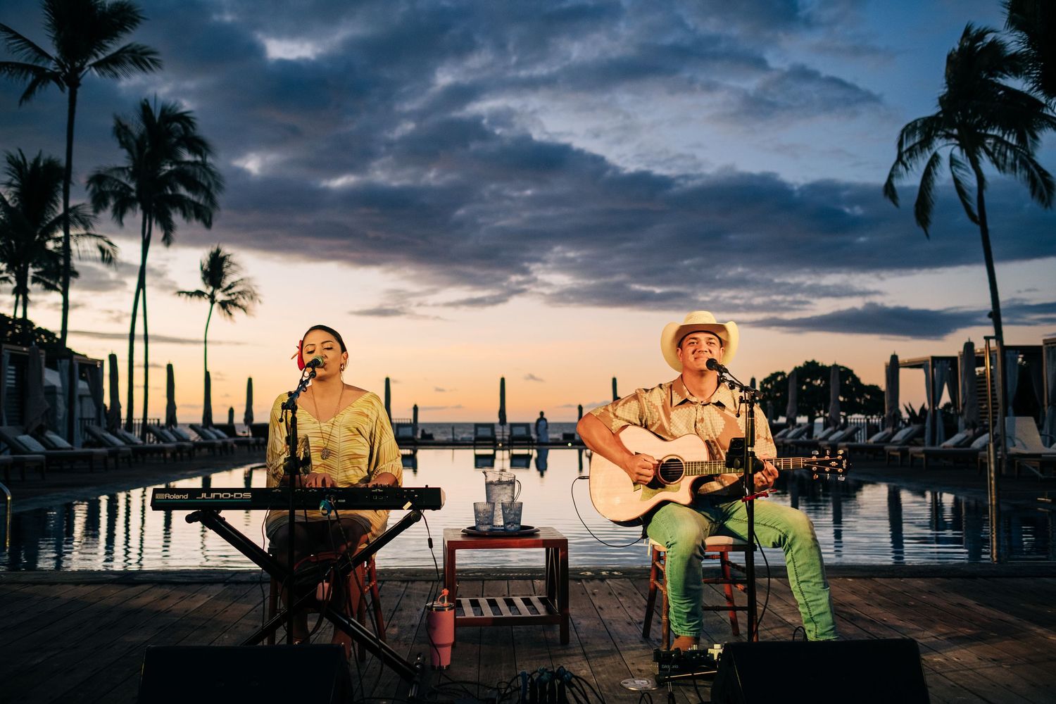 Musicians performing at sunset by the marina with palm trees in silhouette at a Four Seasons Hualalai Event.