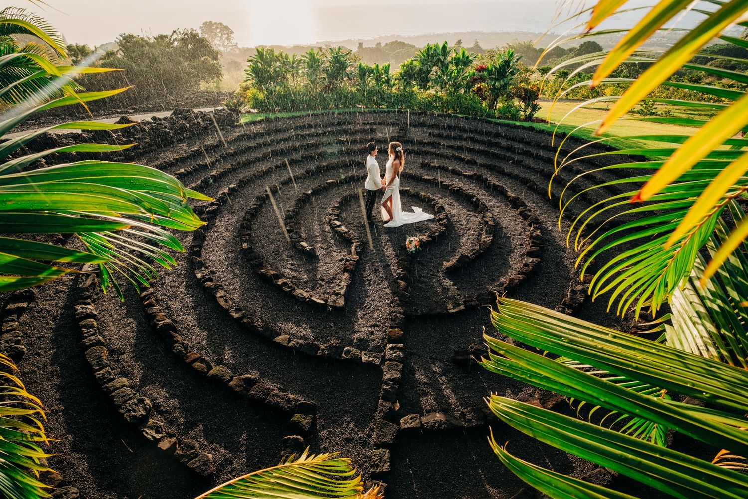 Wedding photography at a tropical garden maze with palm fronds and stone seating at Holualoa Inn, Kona, Big Island Hawaii.