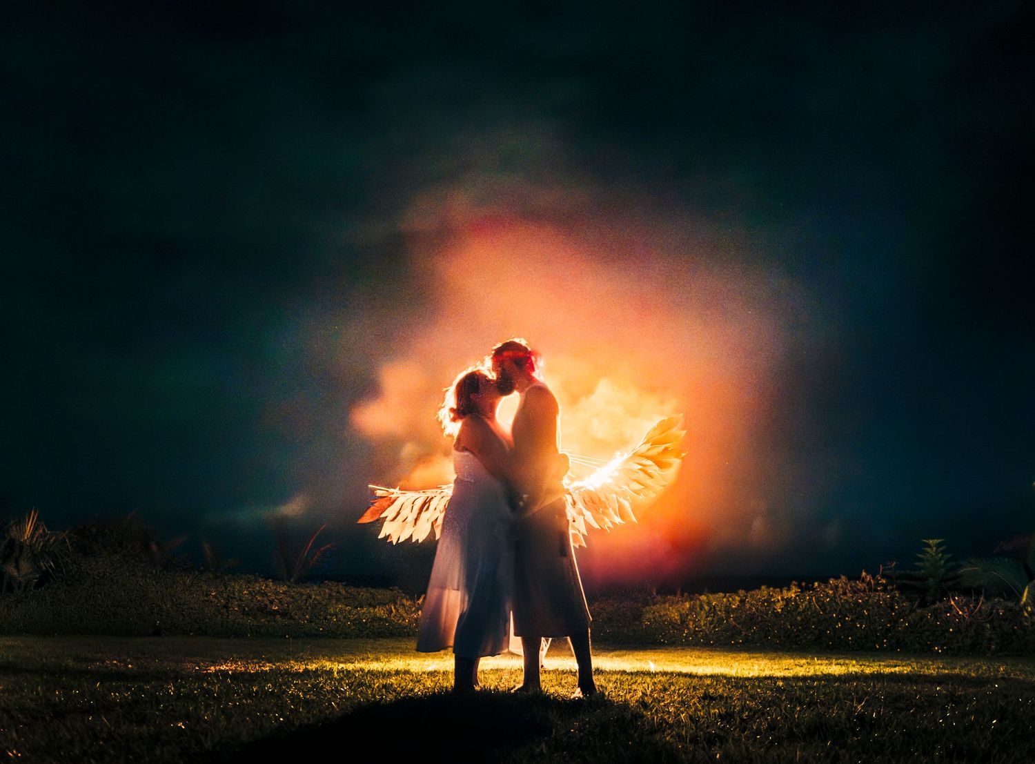 Dramatic nighttime wedding photos with silhouettes against bright orange burning phoenix on the Big Island of Hawaii.