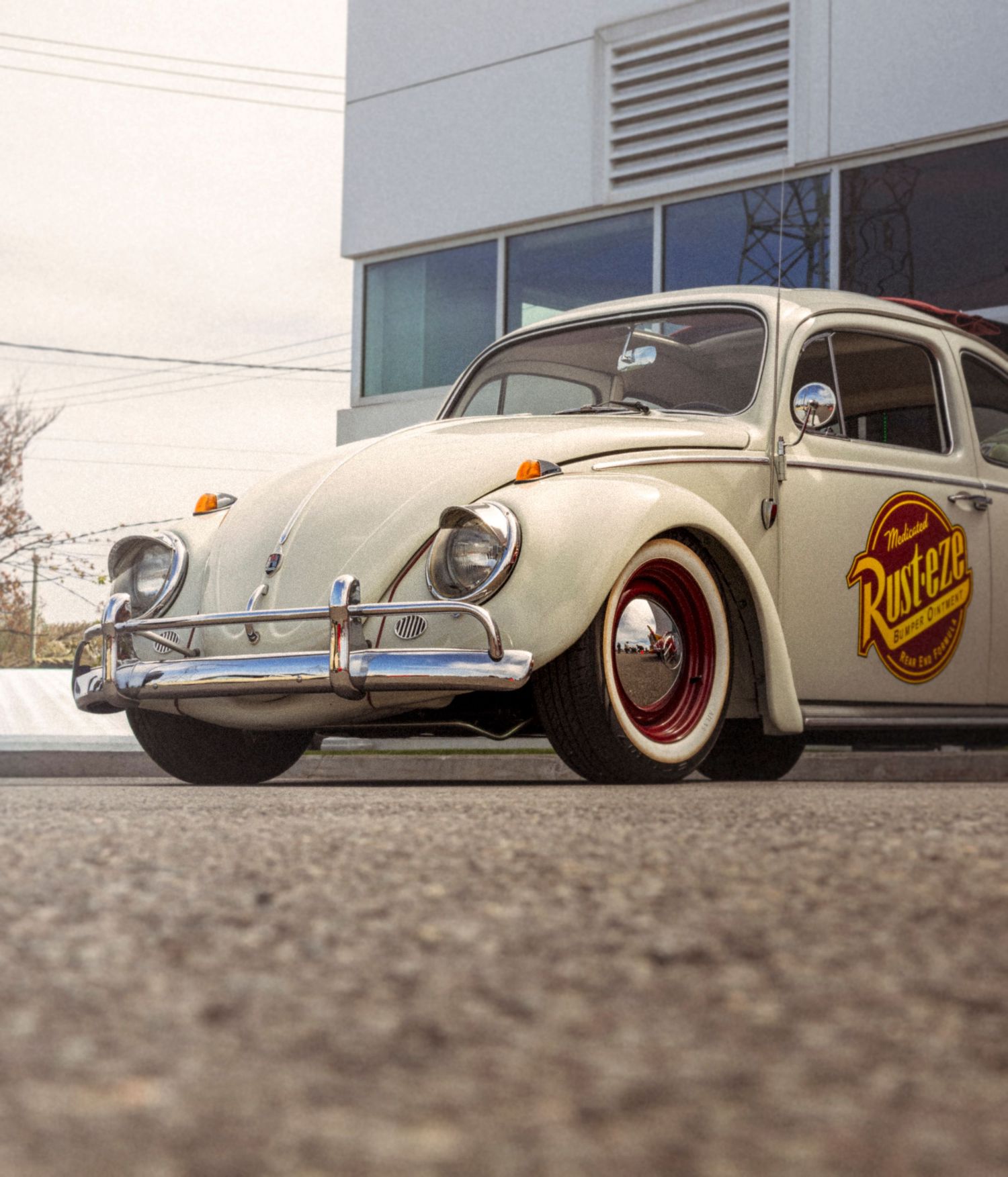 A cream vintage Volkswagen Beetle with chrome bumpers, red wheels and a Rust-Eze logo parked outside a modern building.