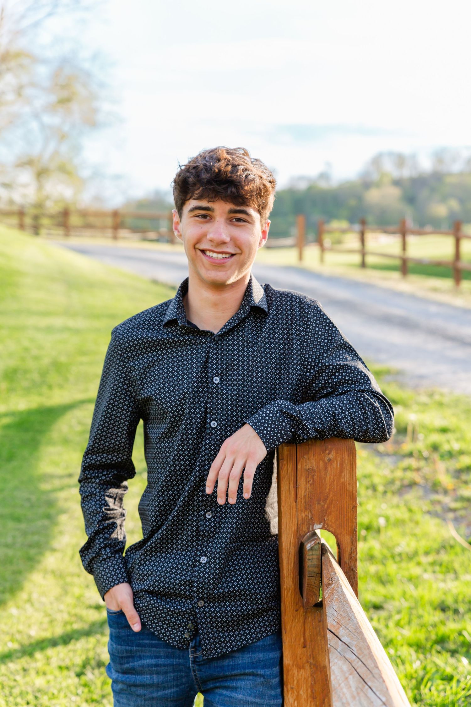 Casual portrait session in a rural setting with wooden fence and natural lighting.