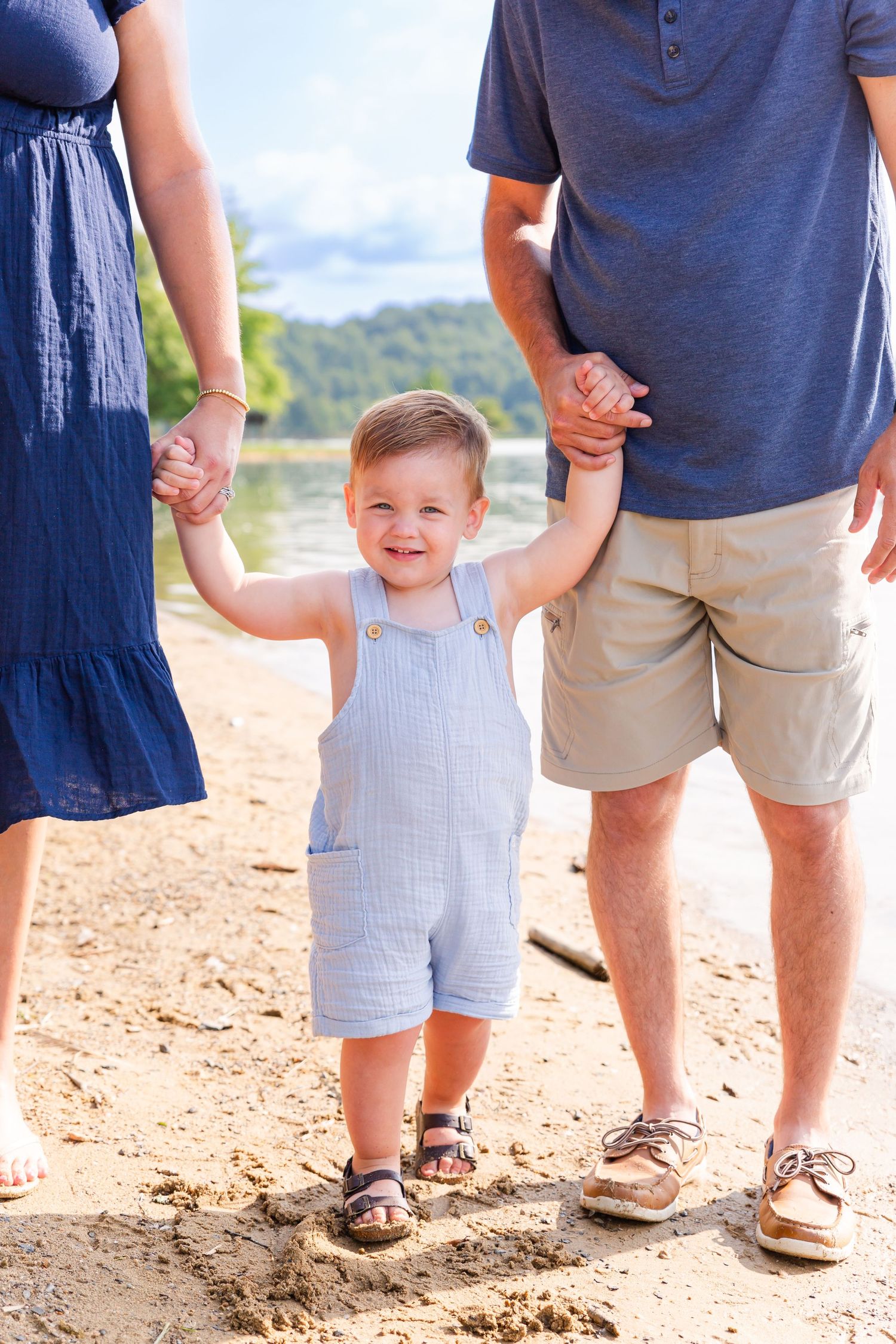 Parent and child walking together on a sandy beach path in summer.