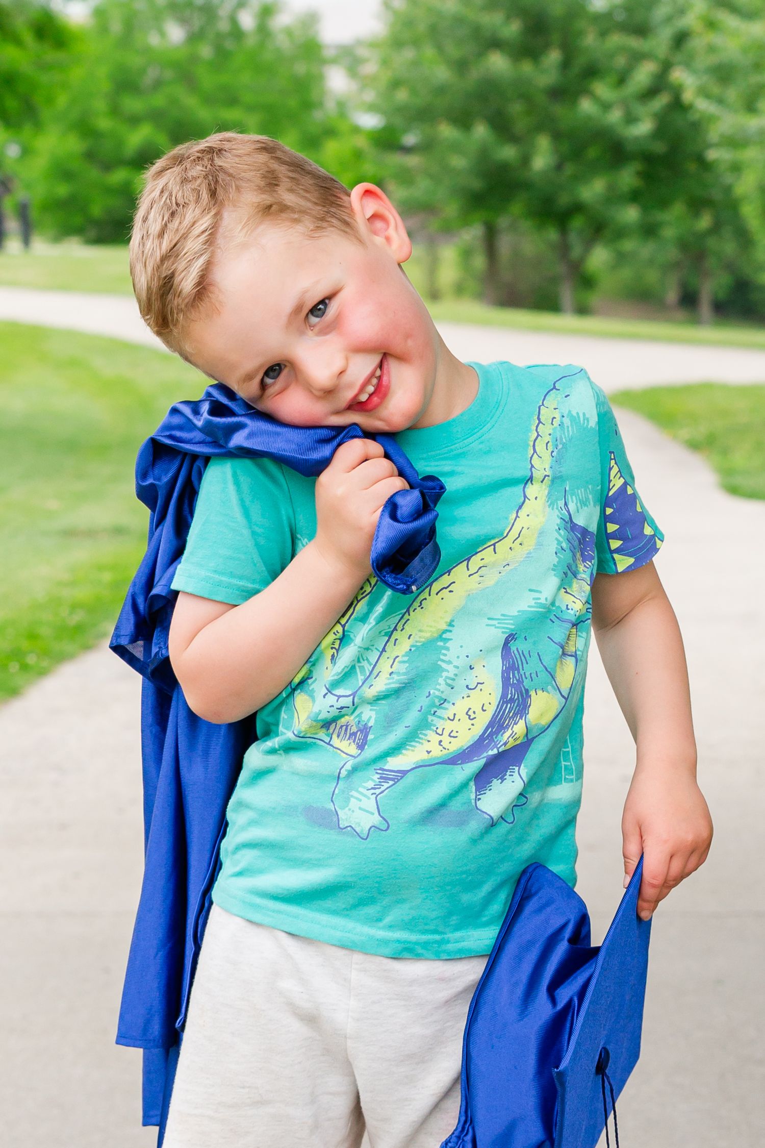 A turquoise fish-print t-shirt pairs with a blue graduation gown in casual outdoor portraits.