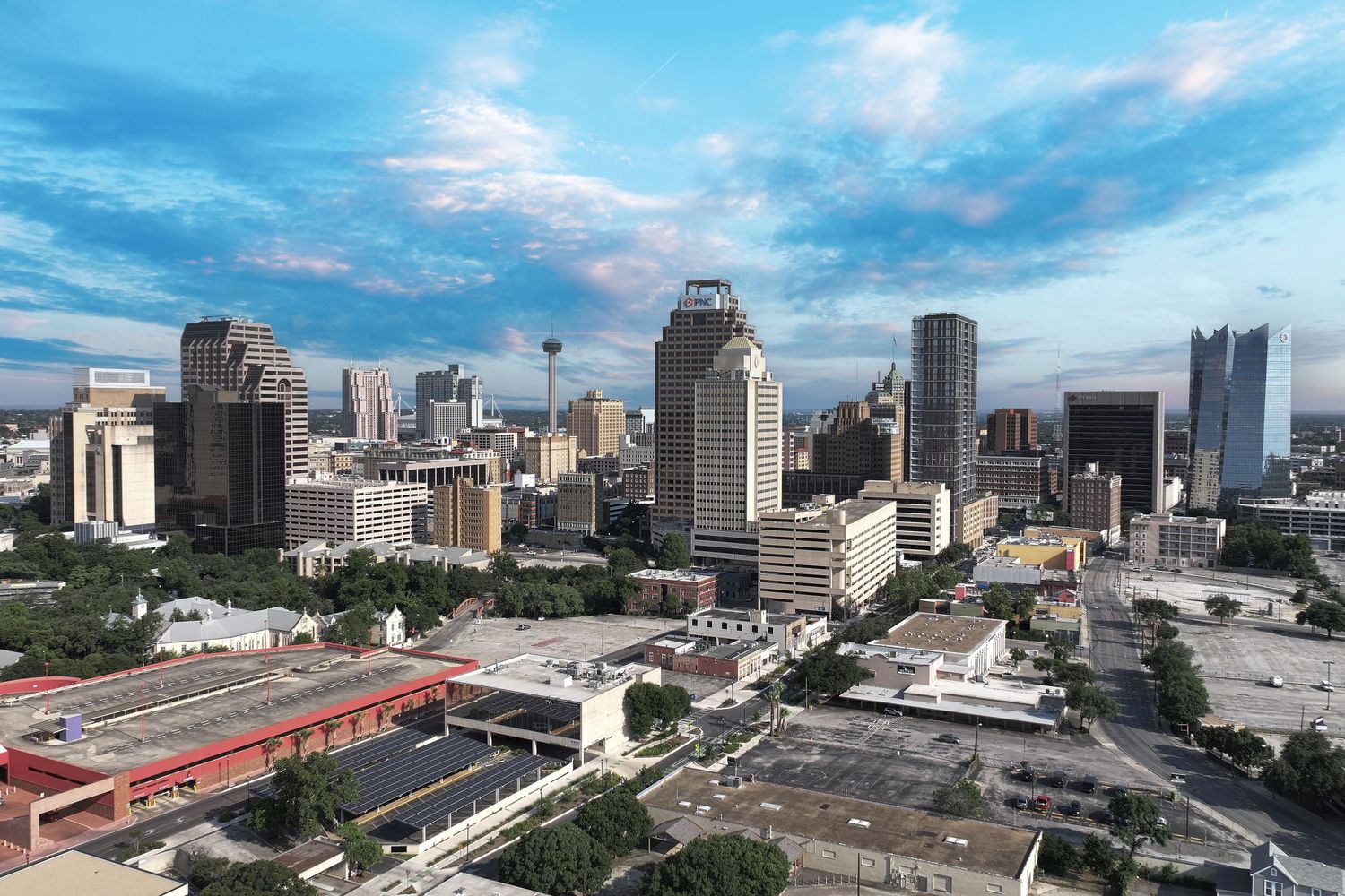Aerial view of San Antonio, Texas skyline with modern skyscrapers under a partly cloudy blue sky.