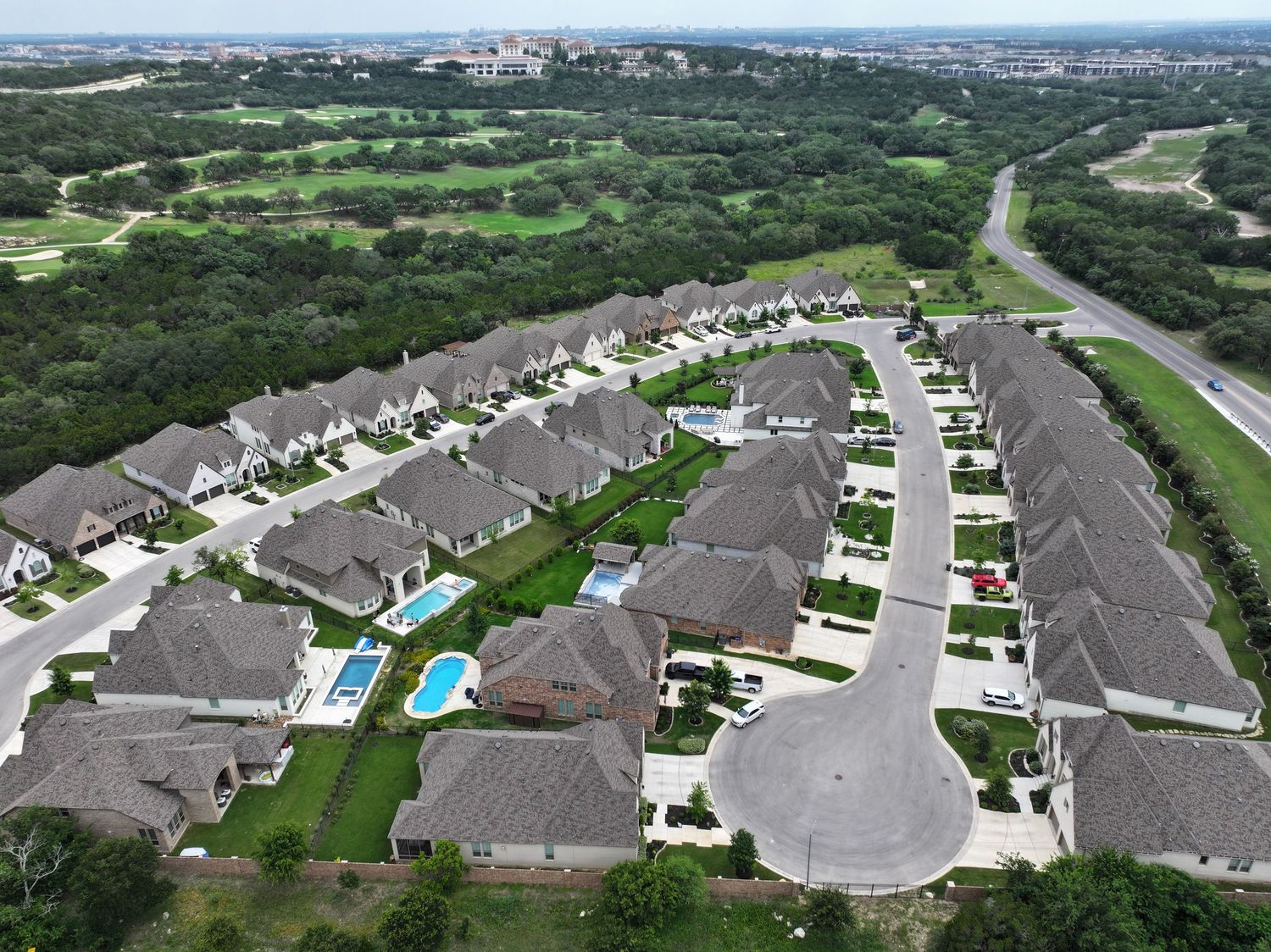 Aerial view of a small residential community with small homes, and lush greenery near a Cedar Creek golf course.