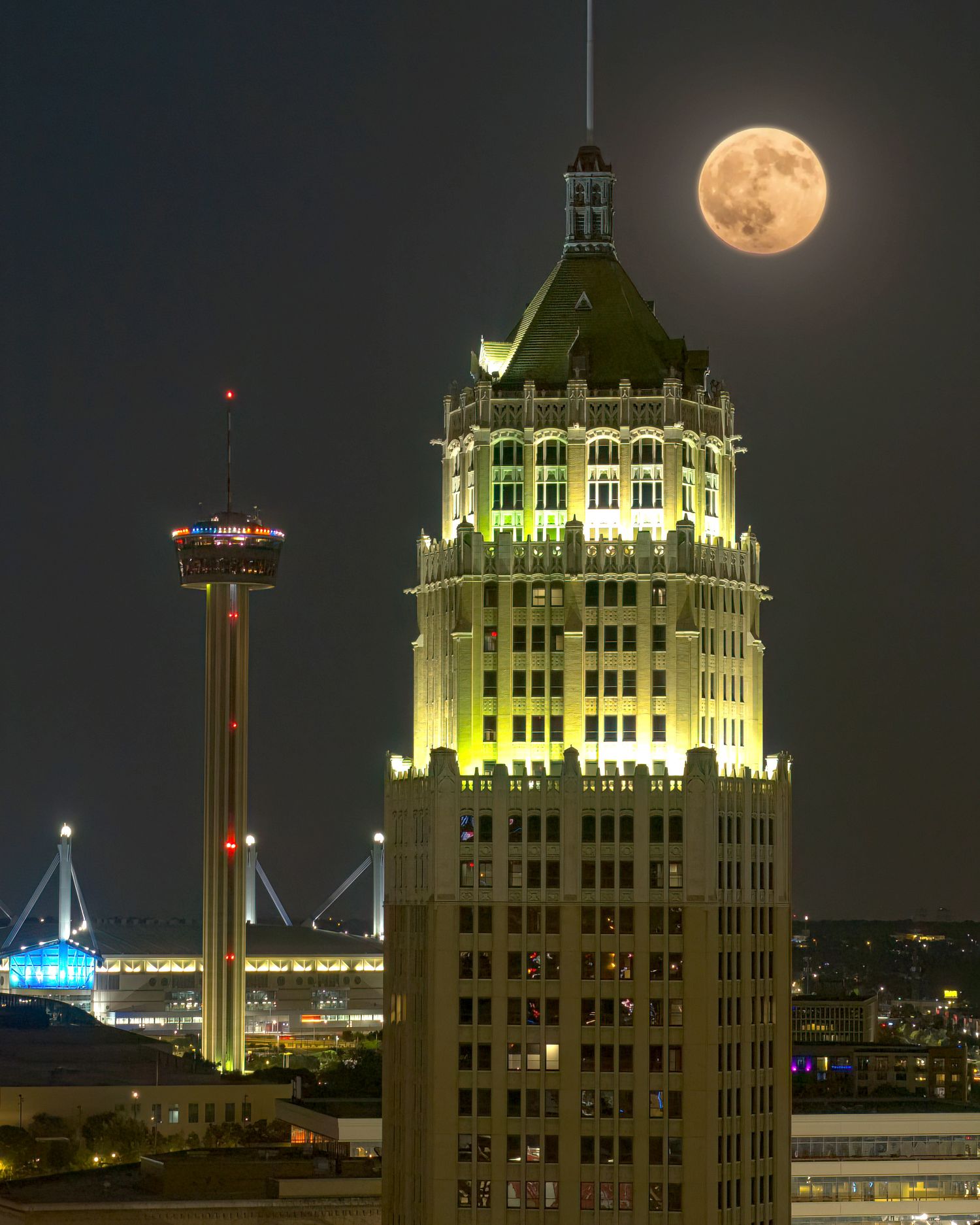 Full moon rising over San Antonio skyline featuring the Tower of the Americas and historic Tower Life building at night.