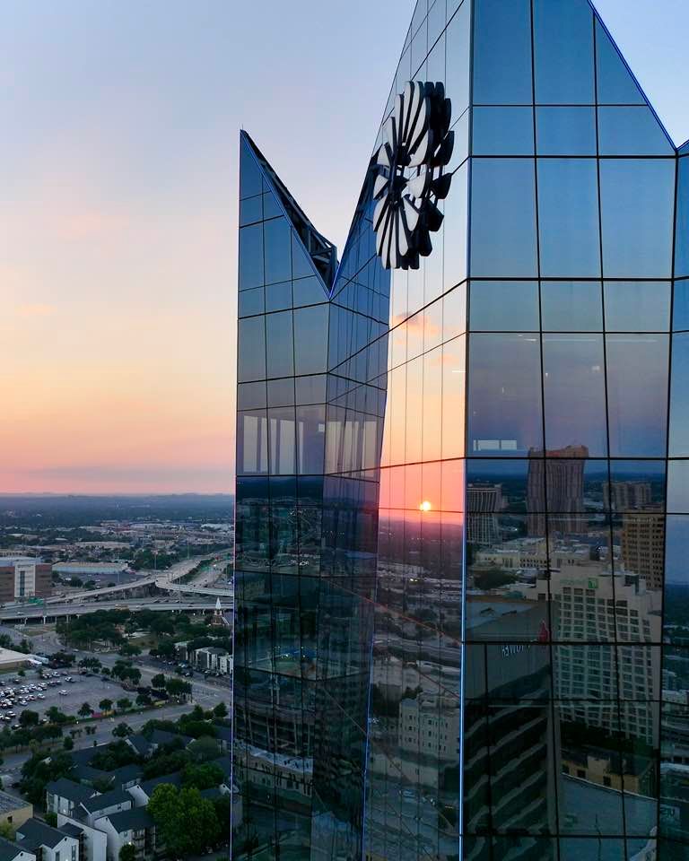 Aerial view of the Frost building - glass skyscraper reflecting golden sunset with modern architecture.