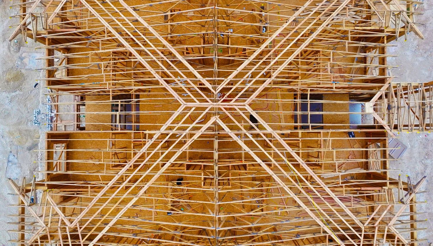 Symmetrical wooden scaffolding framework forming an X-pattern on an apartment building construction site.