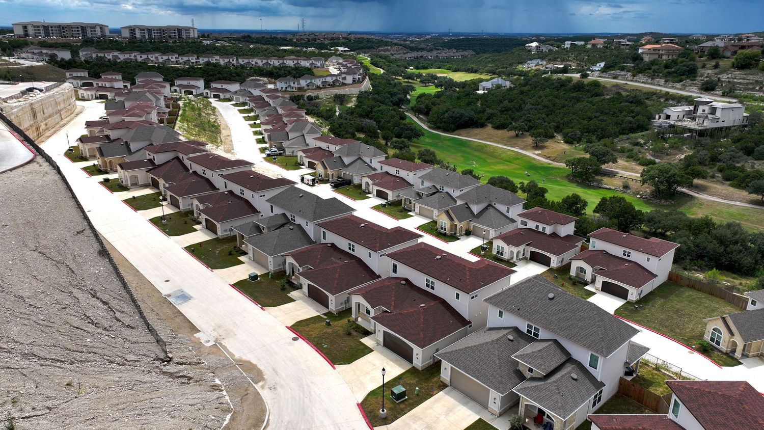 Aerial view of a new residential neighborhood with rows of homes near Cedar Creek golf course under cloudy skies.