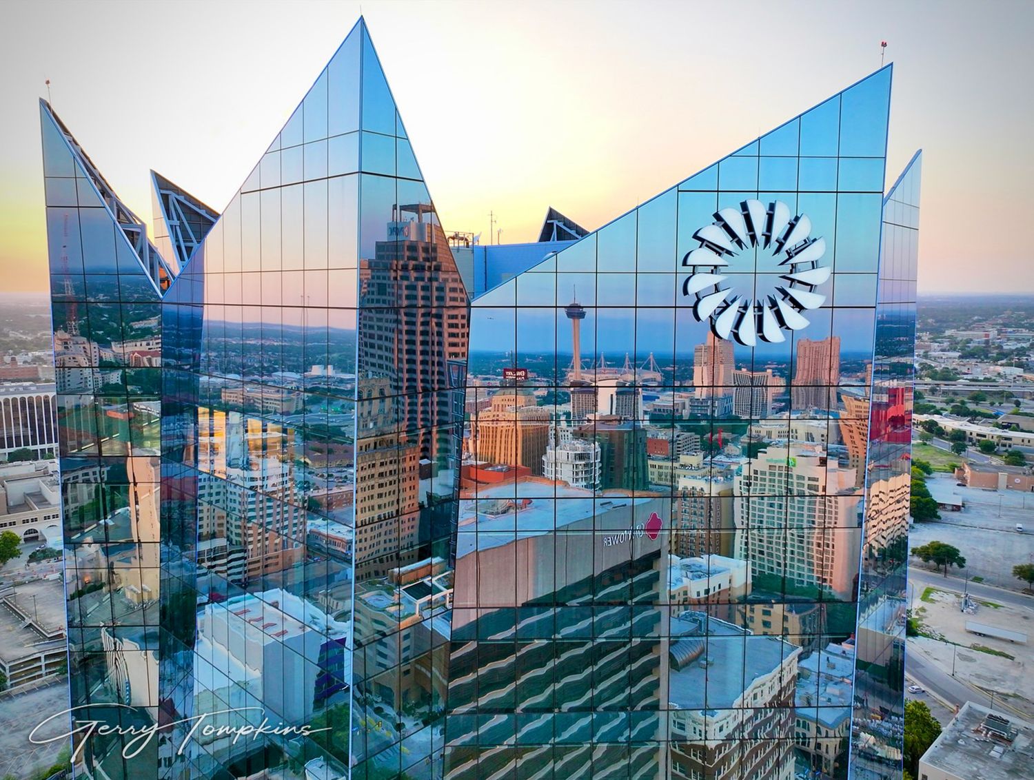 Aerial view of the Frost building - glass skyscraper reflecting golden sunset over a city skyline with modern architecture.