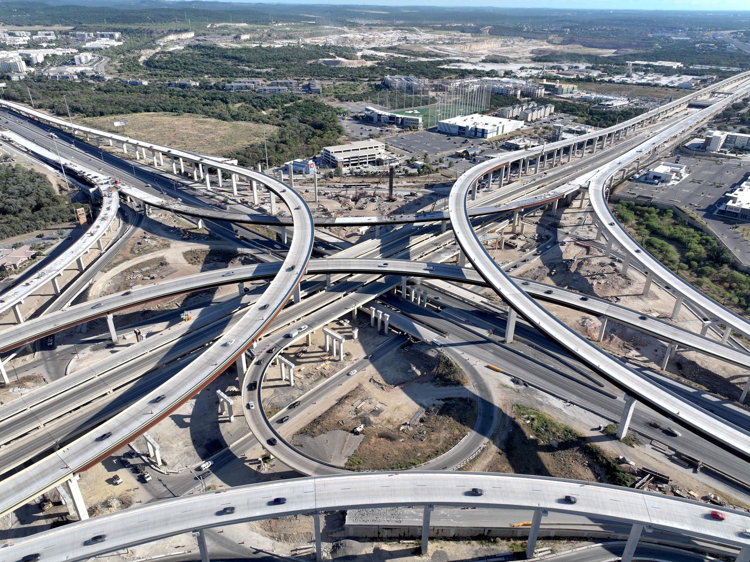 Aerial view of a massive I-10 & 1604 highway interchange with multiple elevated ramps and ongoing construction in an urban area.